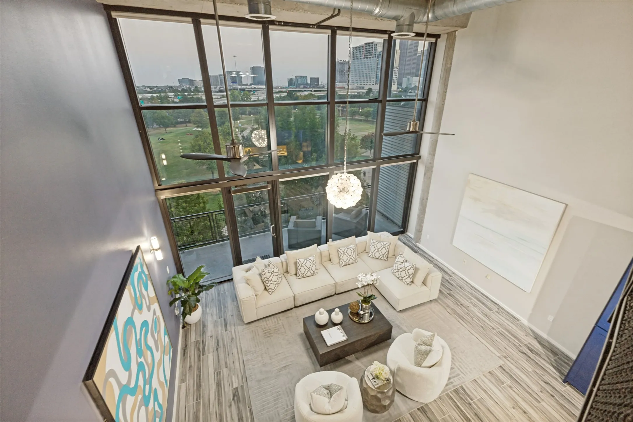 Open-concept living area featuring high ceilings with exposed ductwork, a lofted mezzanine with metal railings, and wood-finish flooring