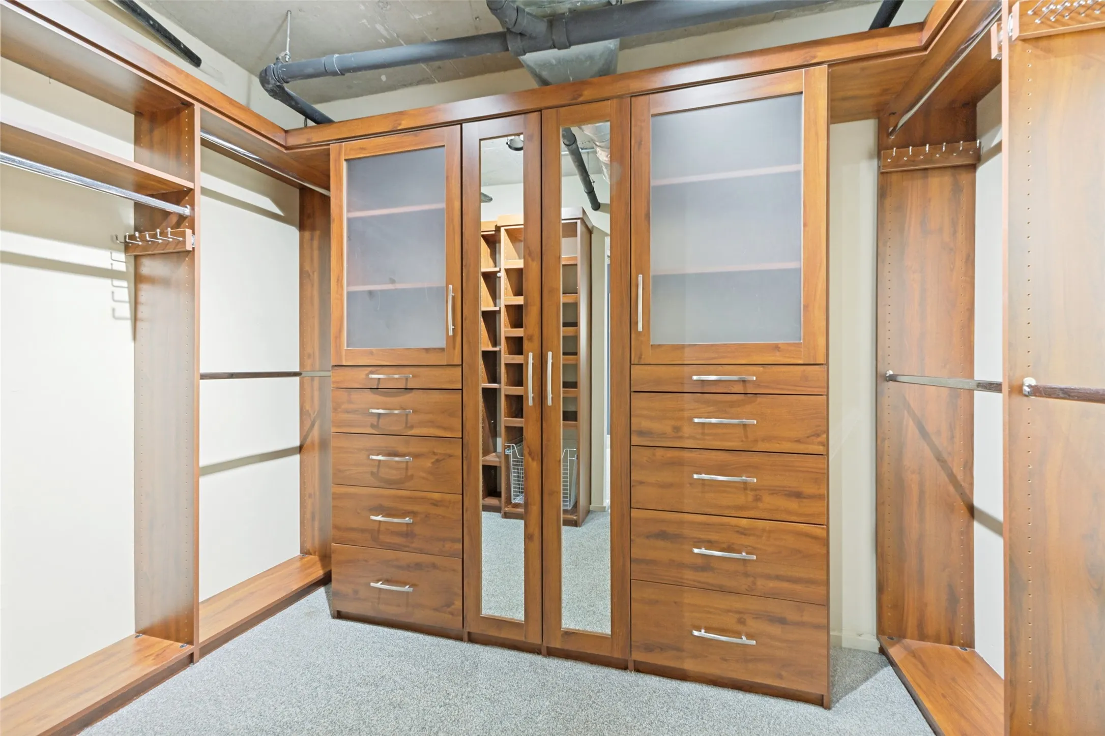 Spacious room featuring a paneled headboard, two wood-finish nightstands, wall-mounted light fixtures, and exposed ceiling joists