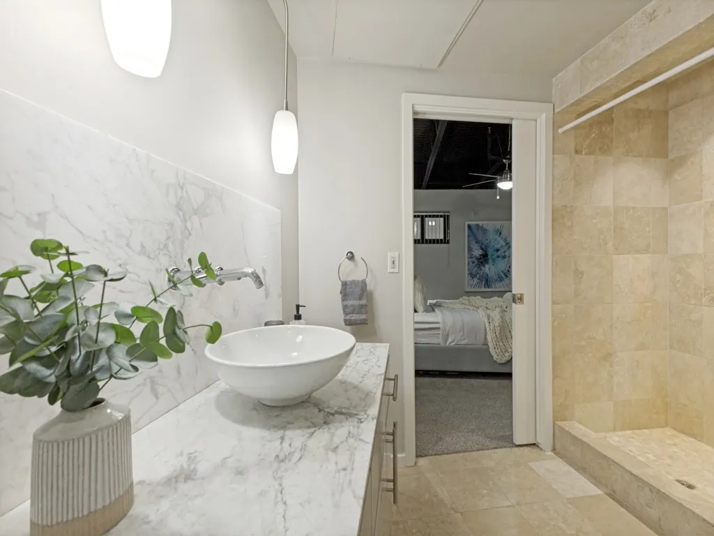 Modern bathroom featuring a vessel sink, wall-mounted faucet, and a large walk-in shower with tile surround