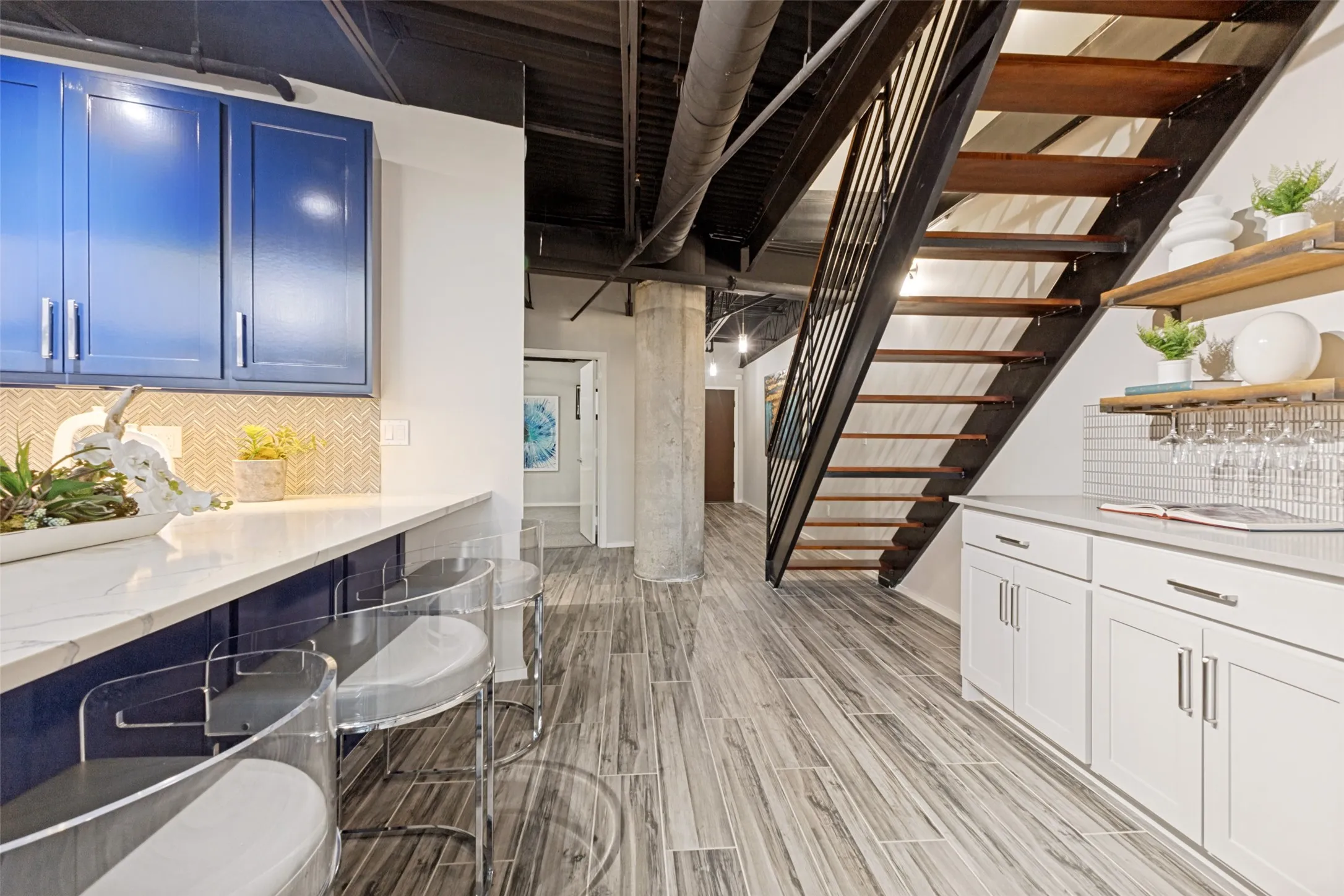 Spacious room featuring exposed concrete ceilings with track lighting, a ceiling fan, and light-colored carpet flooring