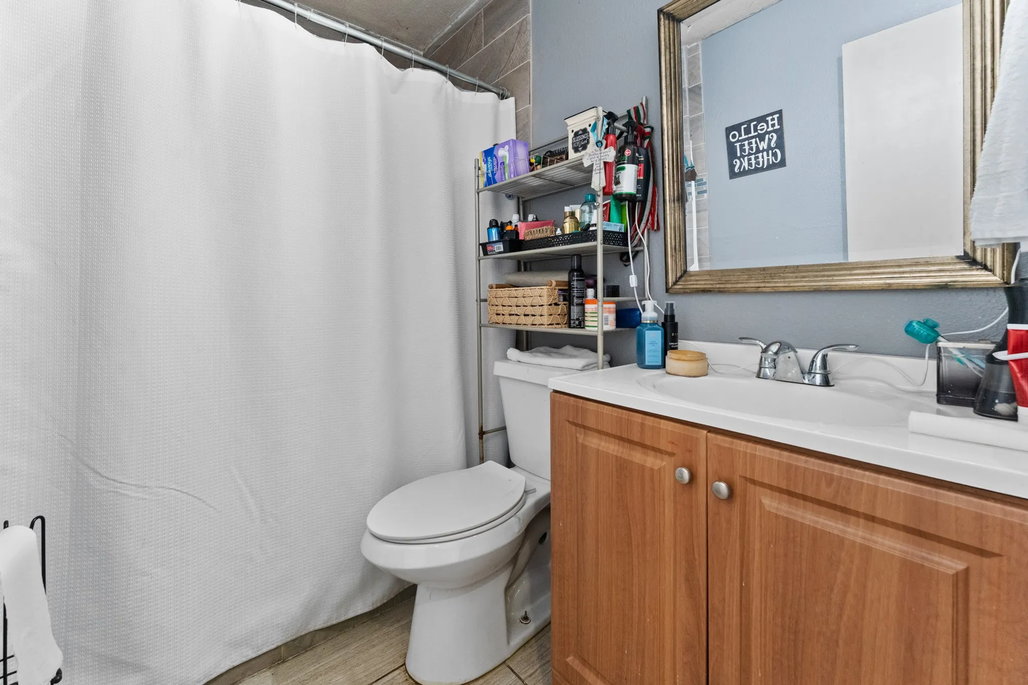 Functional bathroom featuring a wood-finish vanity with dual cabinet storage, white countertop, and chrome faucet fixtures