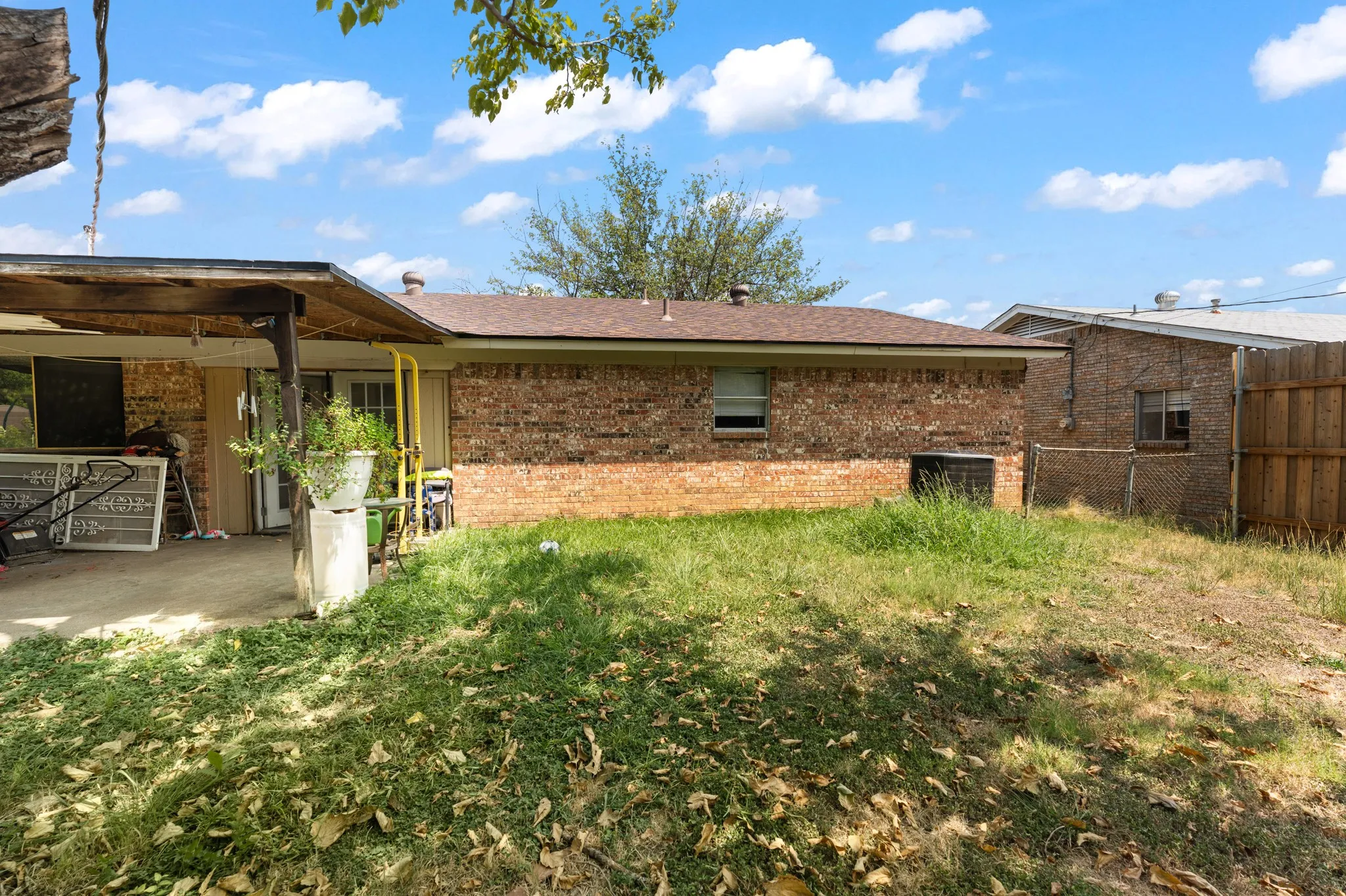 Brick exterior with a covered patio and a partially fenced yard