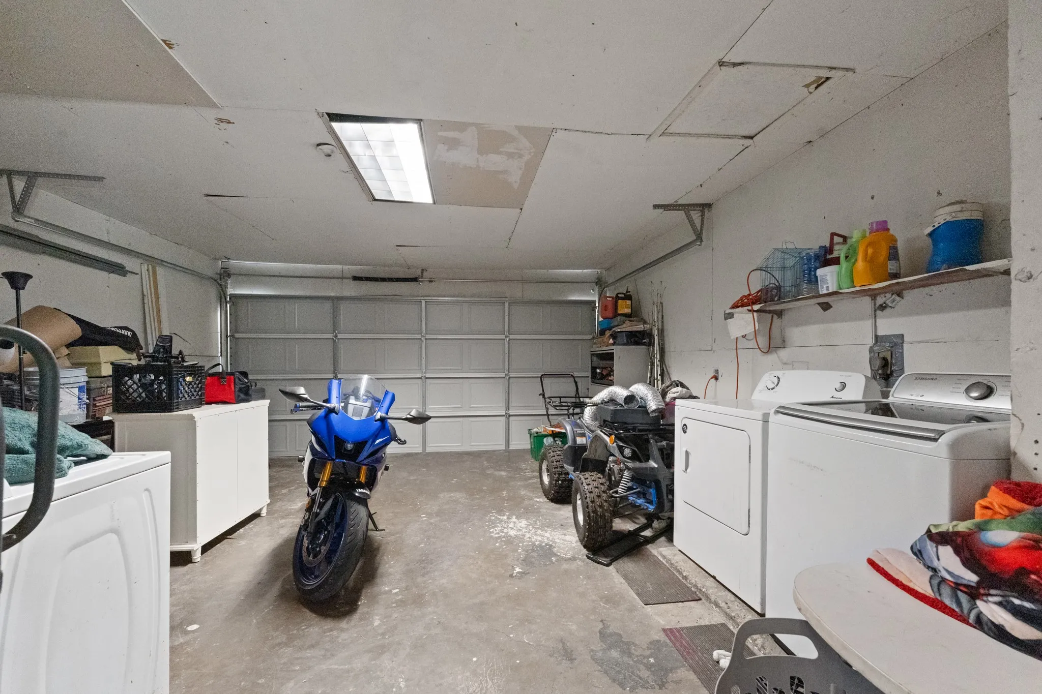 Garage interior featuring a sectional garage door, concrete flooring, and an overhead fluorescent light fixture