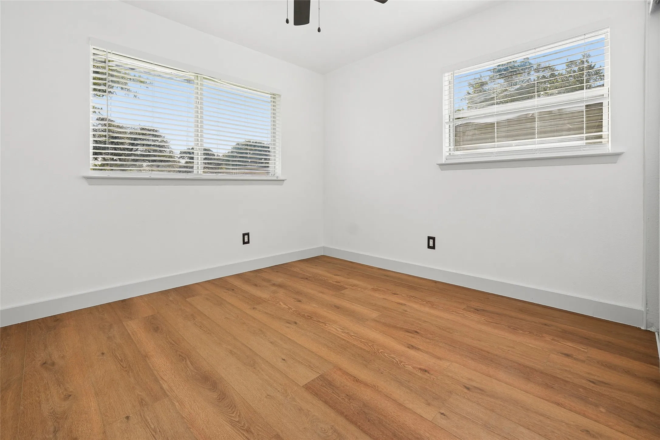 Room featuring wood-finish flooring, white walls, and white trim