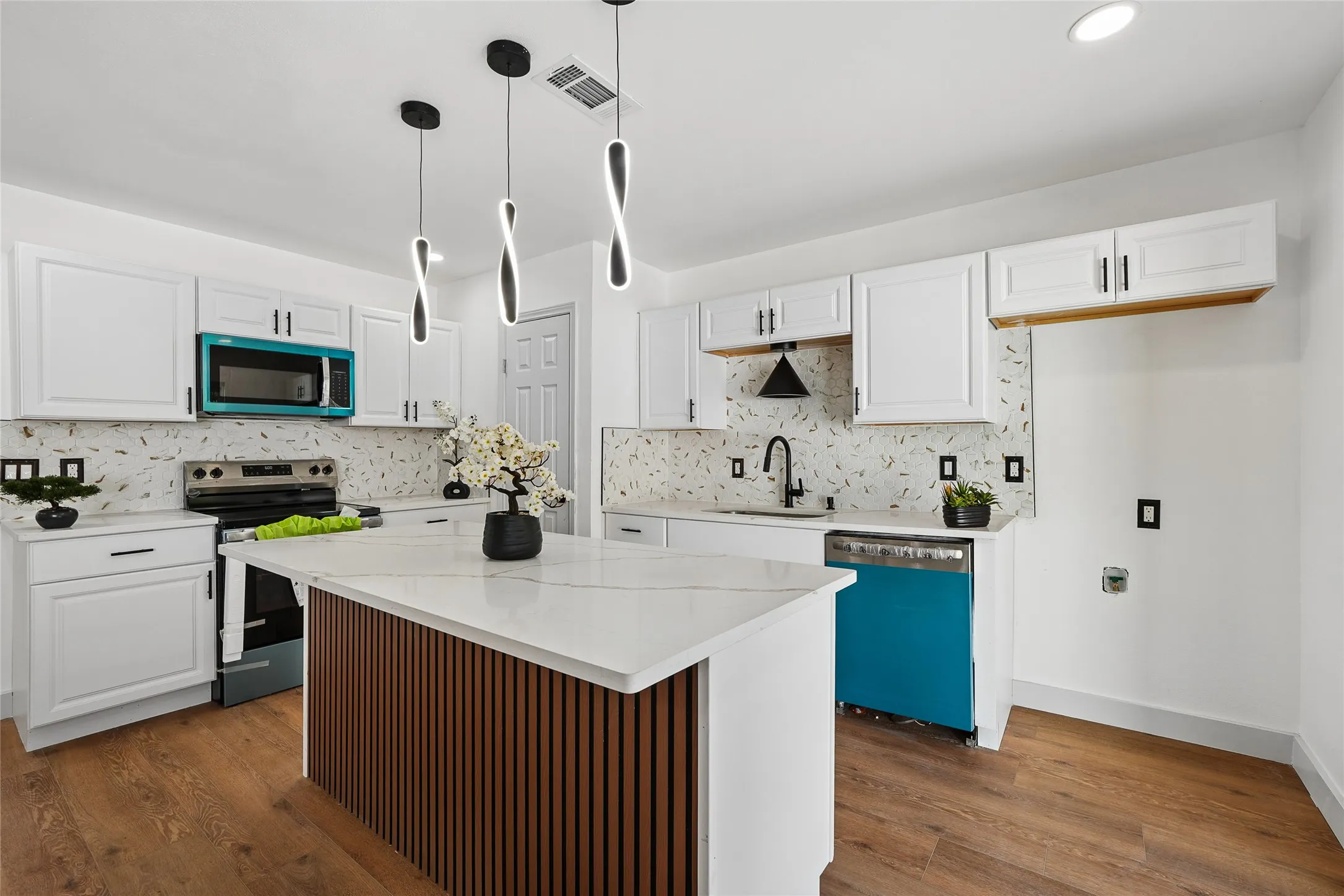 Modern kitchen featuring white cabinetry, a central island with a wood-slat base, quartz countertops, and wood-finish flooring