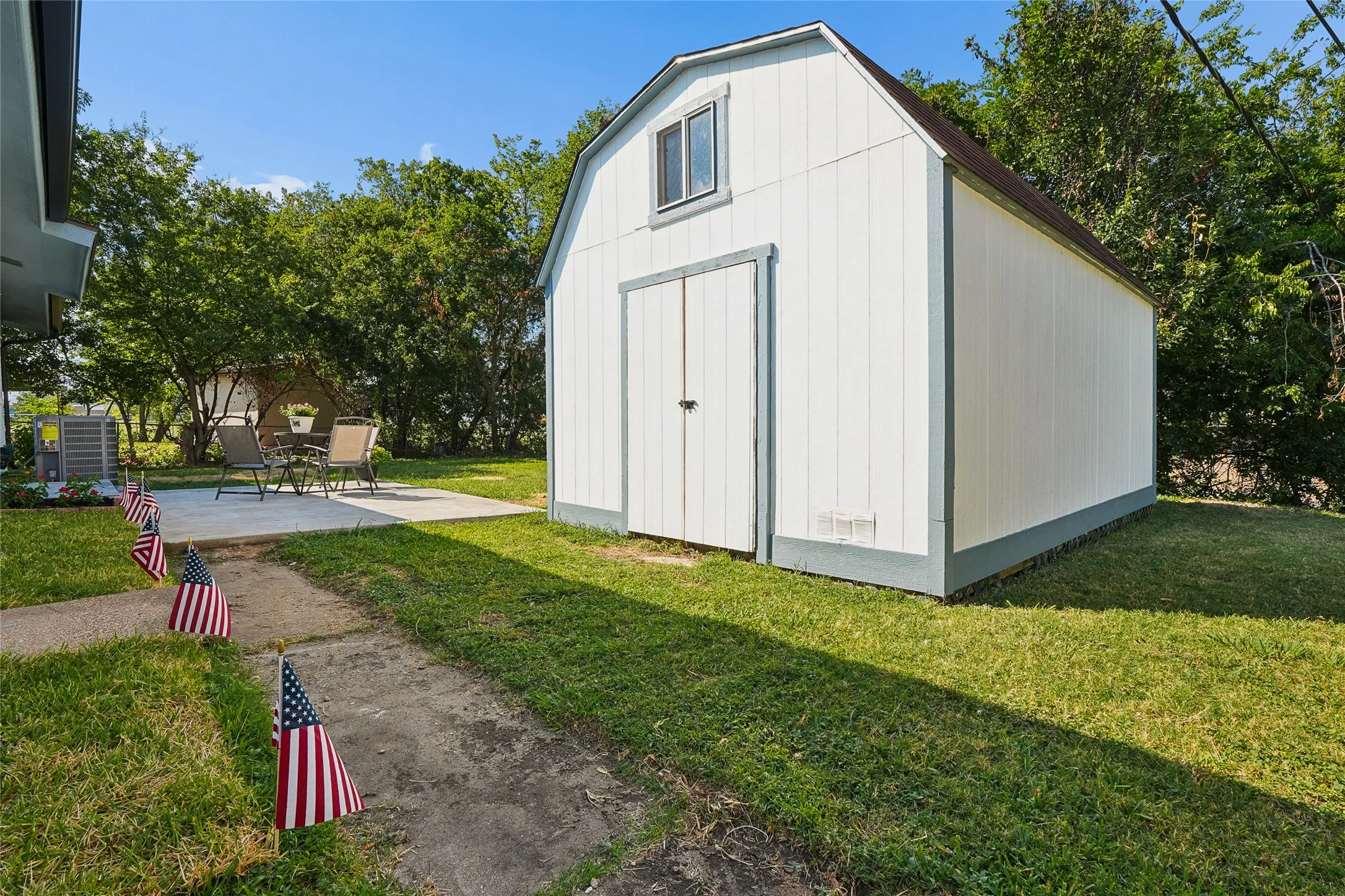 White storage shed with a gambrel roof and upper window
