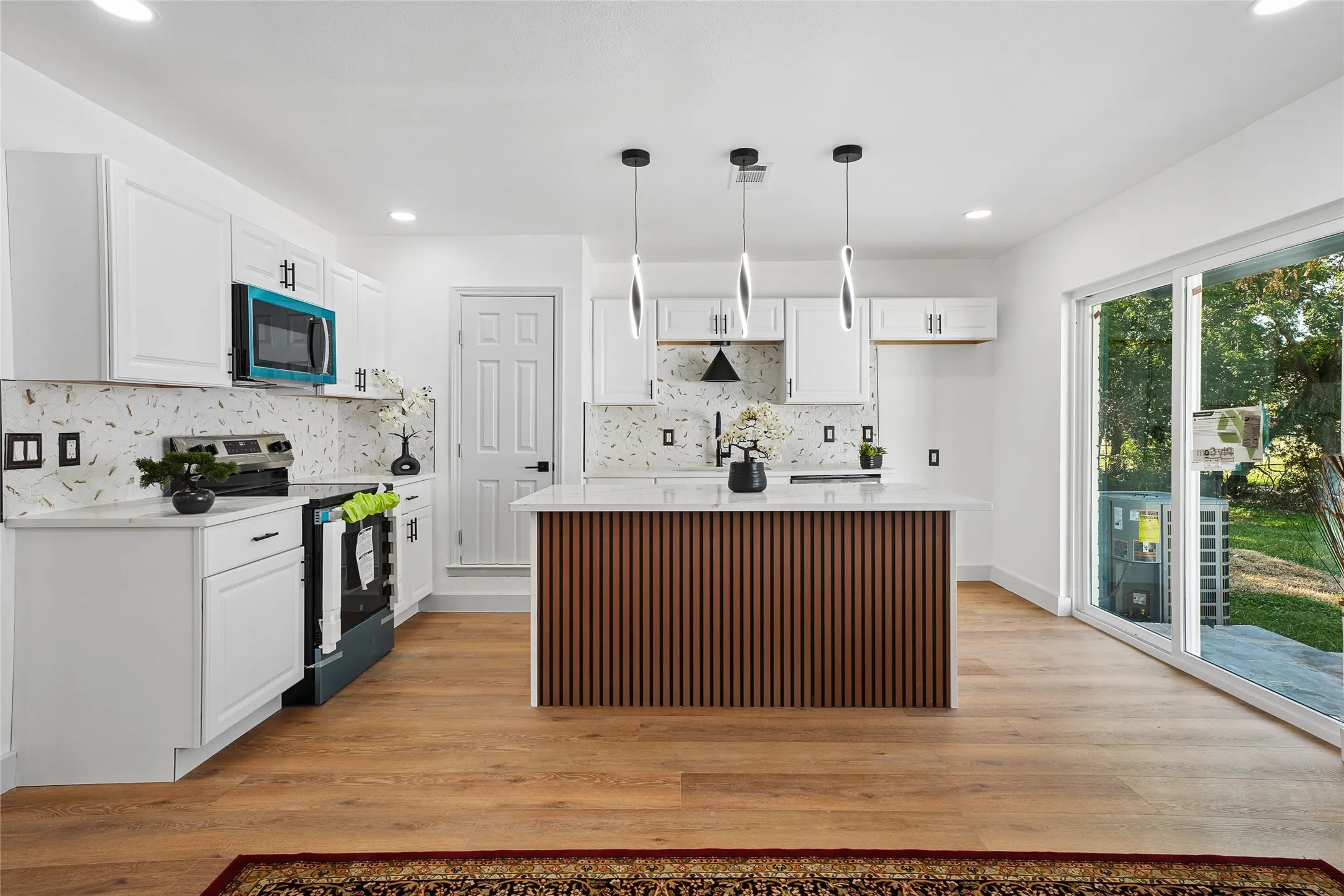 Modern kitchen featuring white cabinetry with brushed nickel hardware, subway tile backsplash, and stainless steel appliances including a built-in microwave