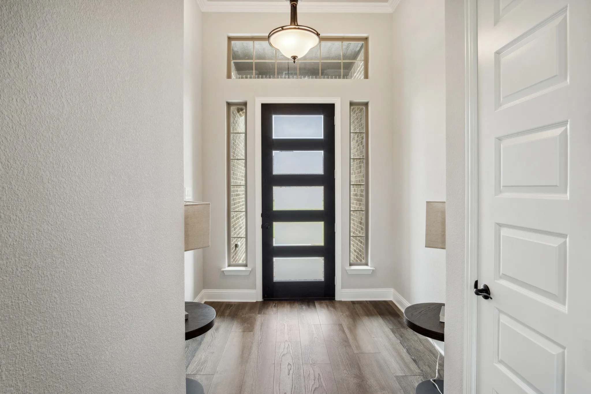Entryway featuring a modern black five-panel glass door, transom window, and vertical sidelight windows