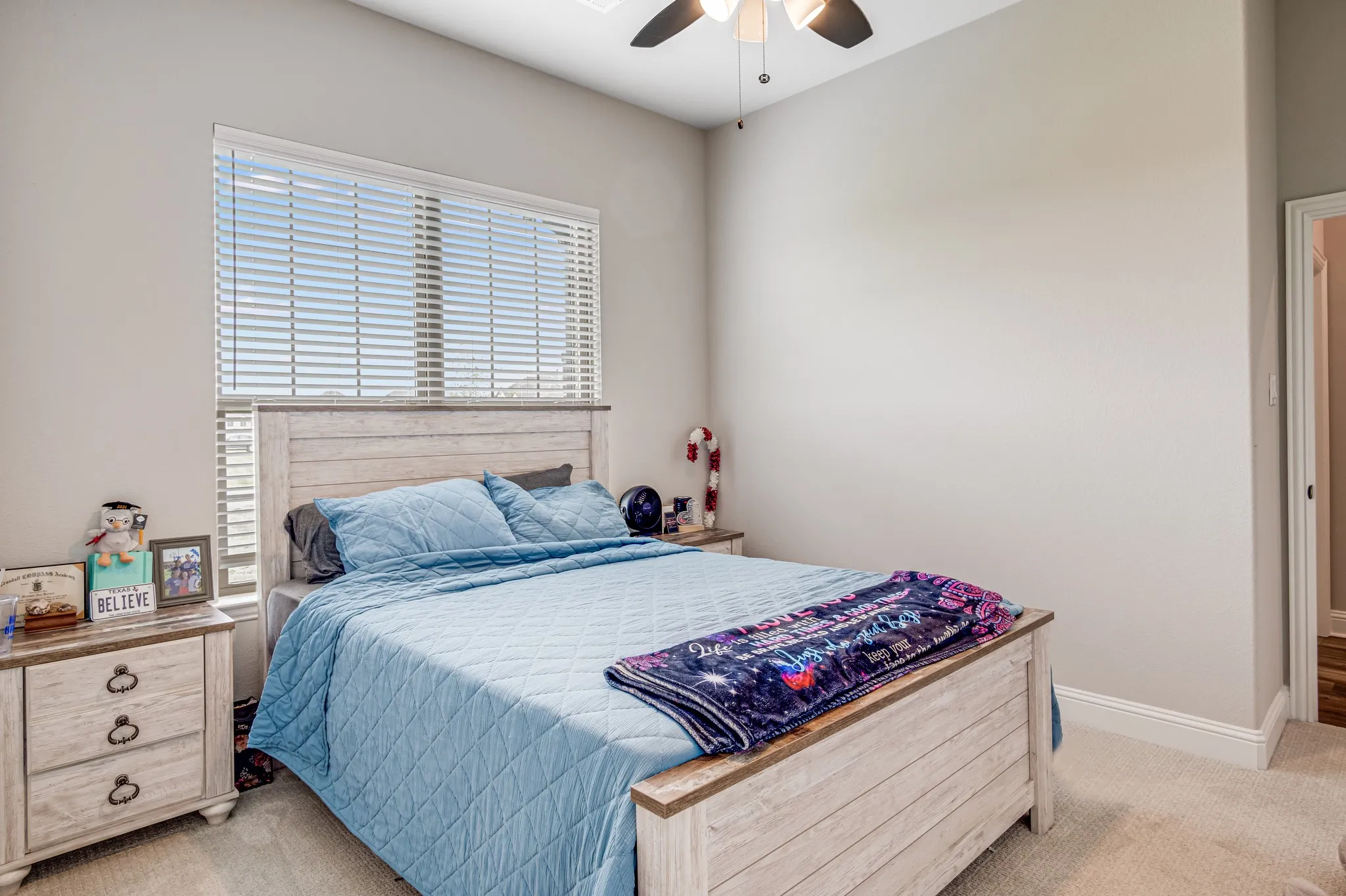 Bedroom featuring neutral-toned walls, a window with horizontal blinds, a ceiling fan with integrated lighting, and carpet flooring