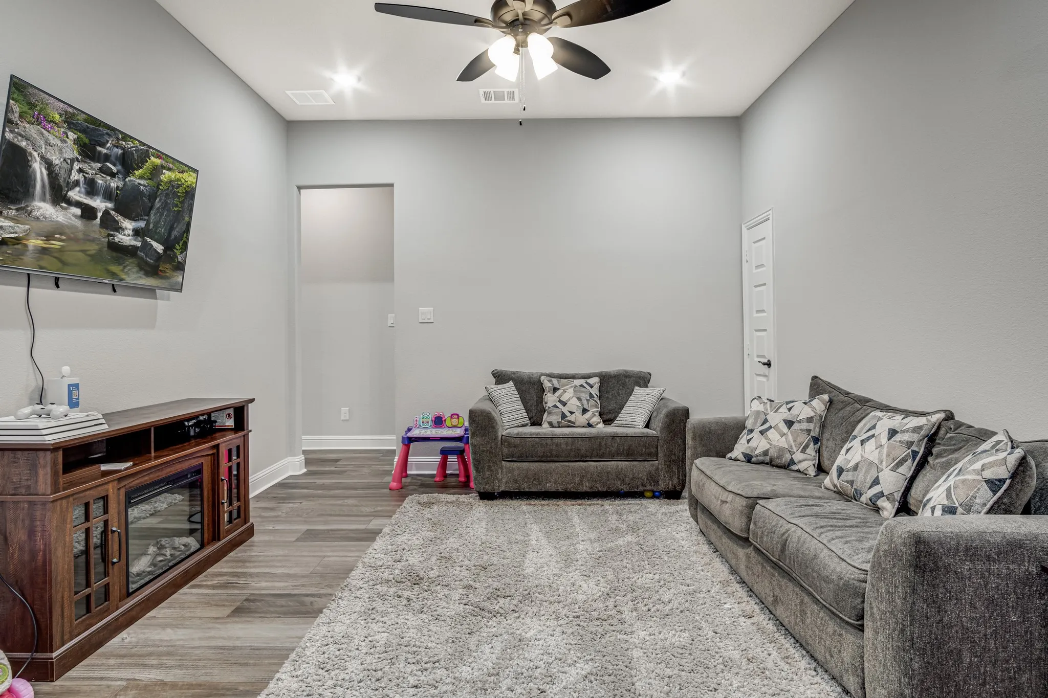 Spacious room featuring wood-finish flooring, recessed lighting, and a ceiling fan