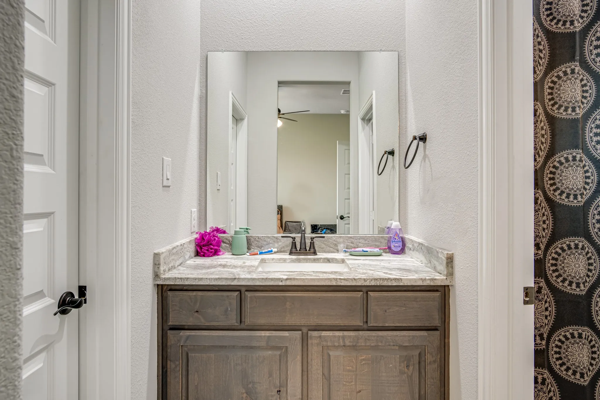 Bathroom vanity featuring a light-toned countertop, an integrated rectangular sink, dark wood-finish cabinetry, and a framed mirror