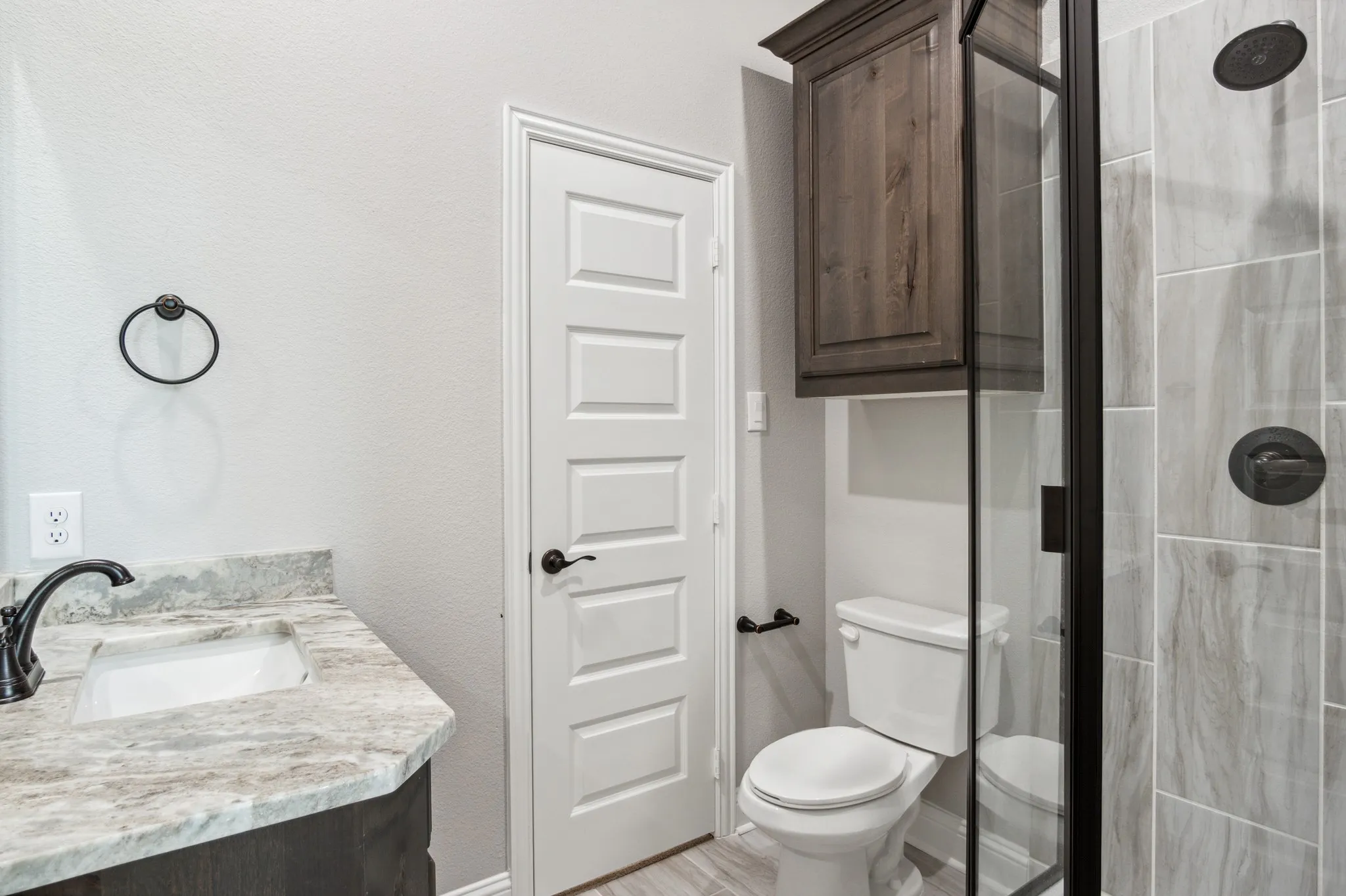 Bathroom with a stone-finish countertop vanity, undermount sink, and dark bronze fixtures