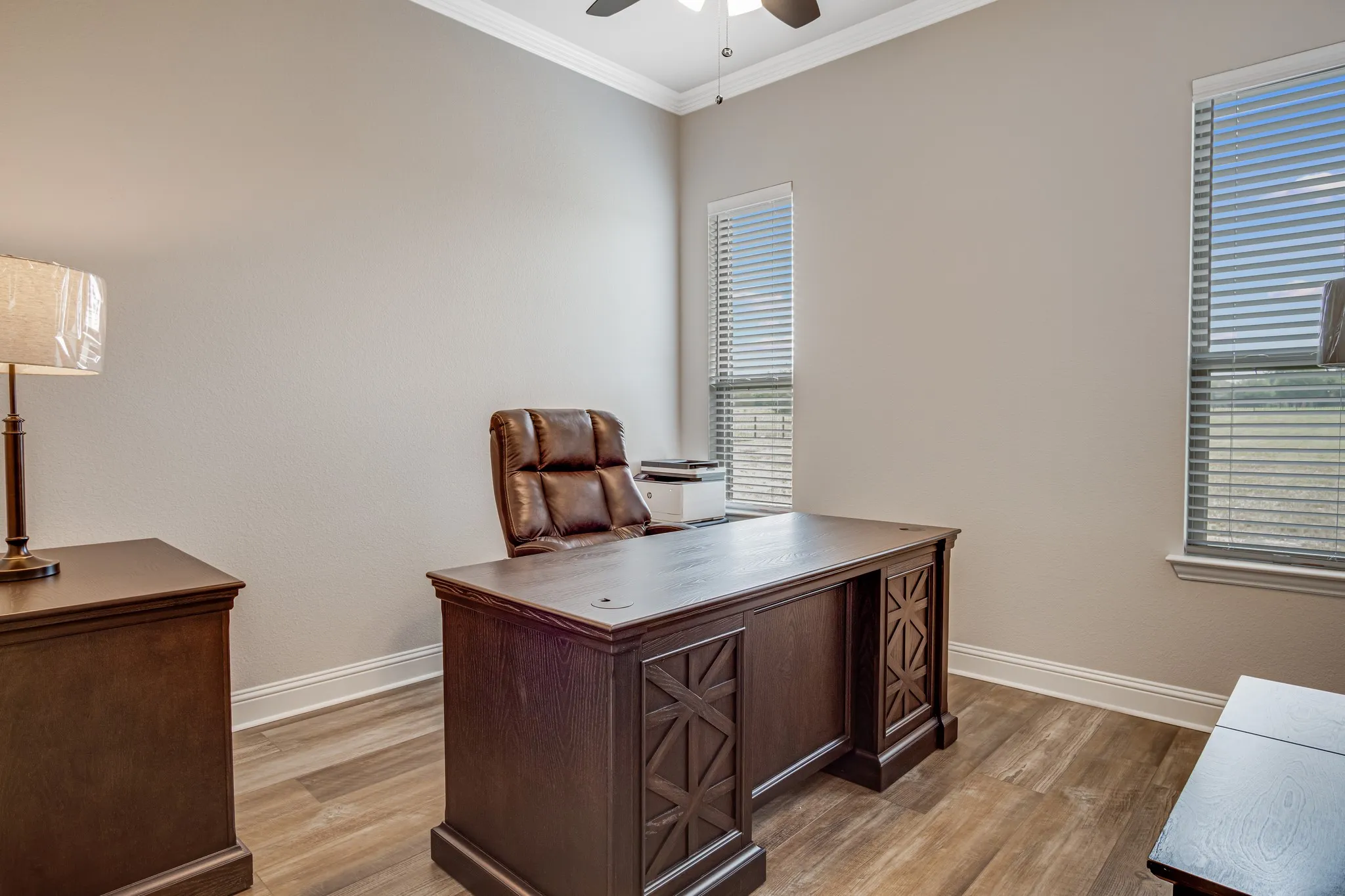 Room featuring wood-finish flooring, two large windows with blinds, and crown molding