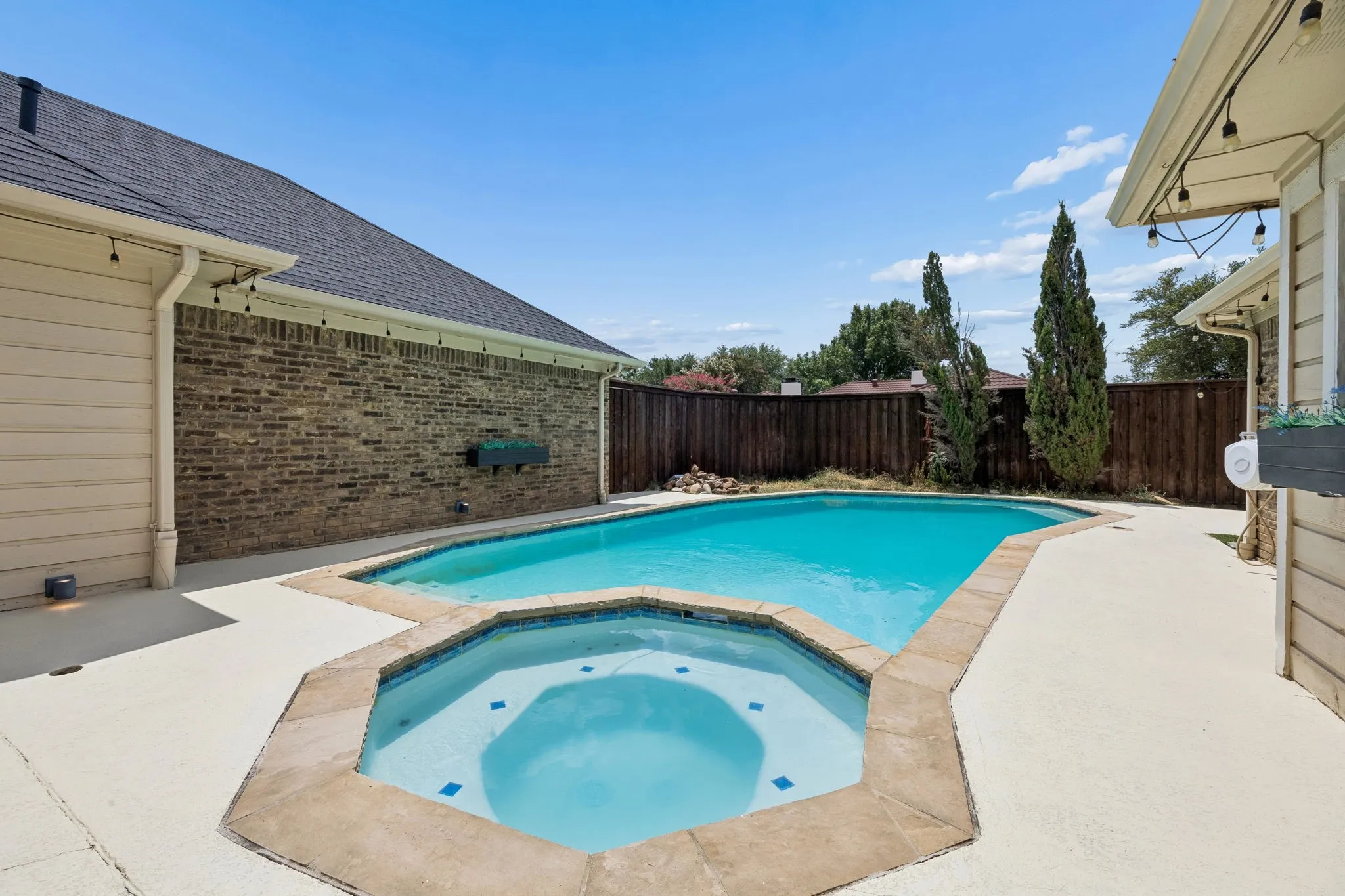 Backyard oasis featuring a swimming pool, integrated spa, and expansive concrete patio