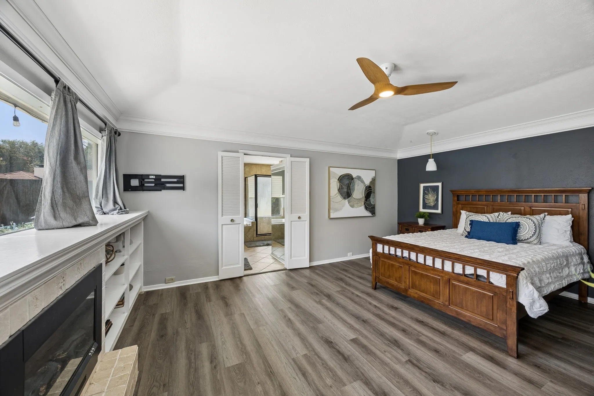 Vaulted ceiling with a wood-finish ceiling fan, wood-finish flooring, built-in shelving, and a wall-mounted electric fireplace
