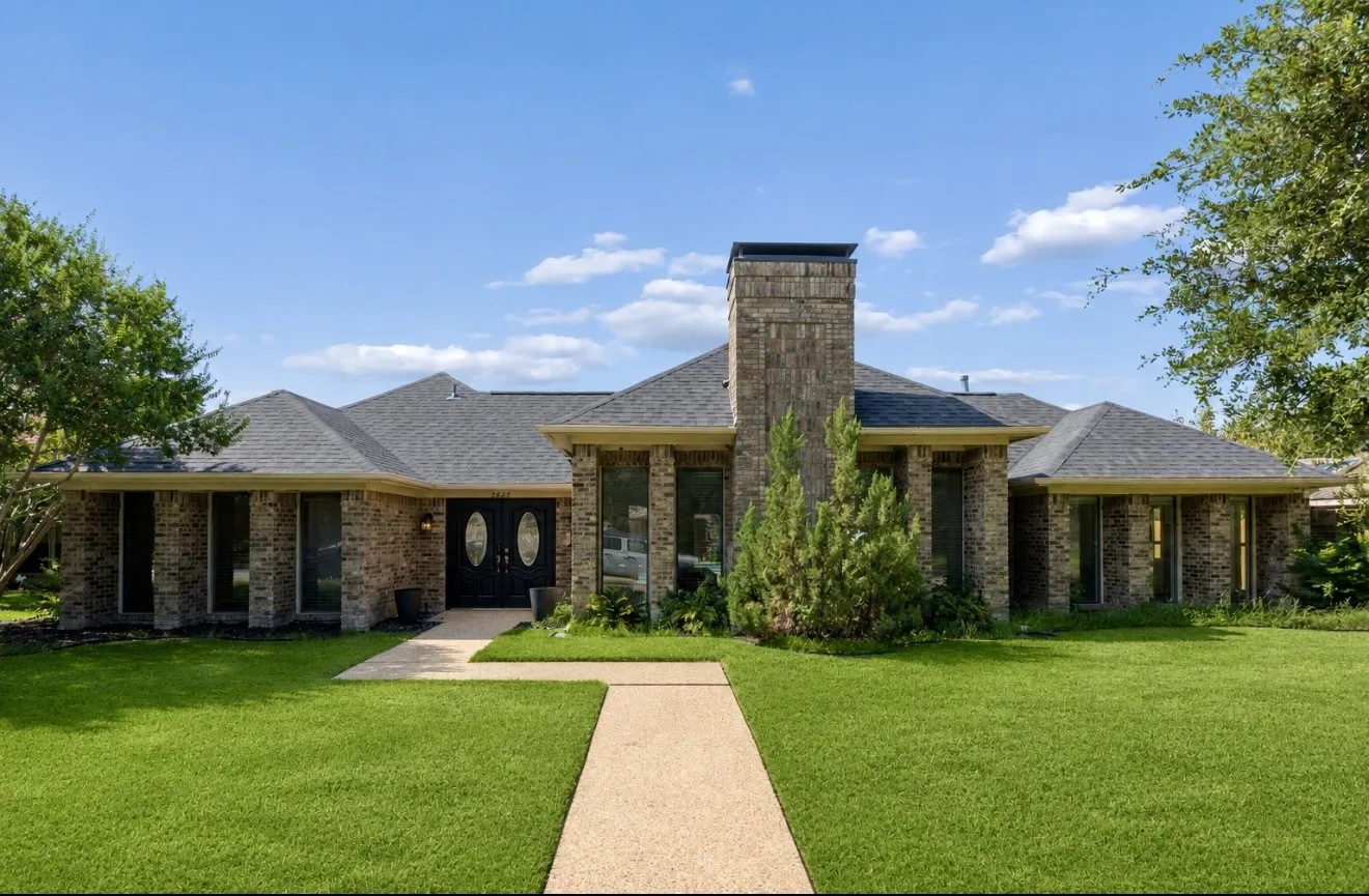 One-story residence featuring a brick exterior, prominent central chimney, and a dark shingle roof