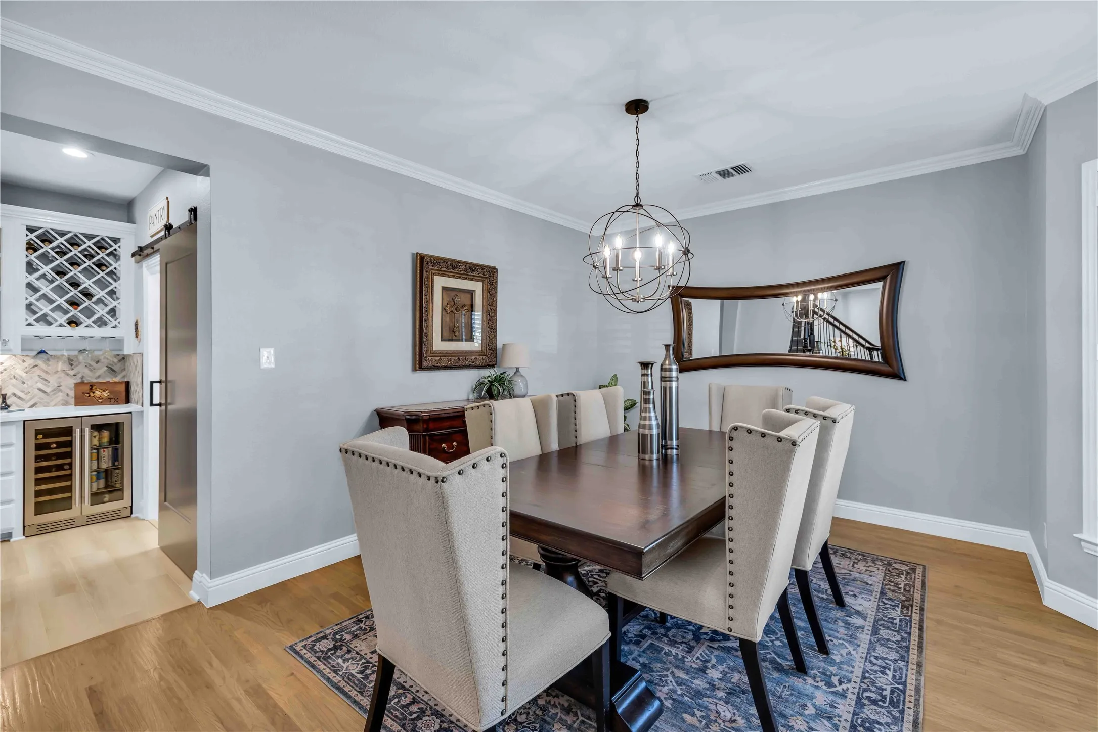 Dining area featuring wood-finish flooring, crown molding, and a contemporary chandelier