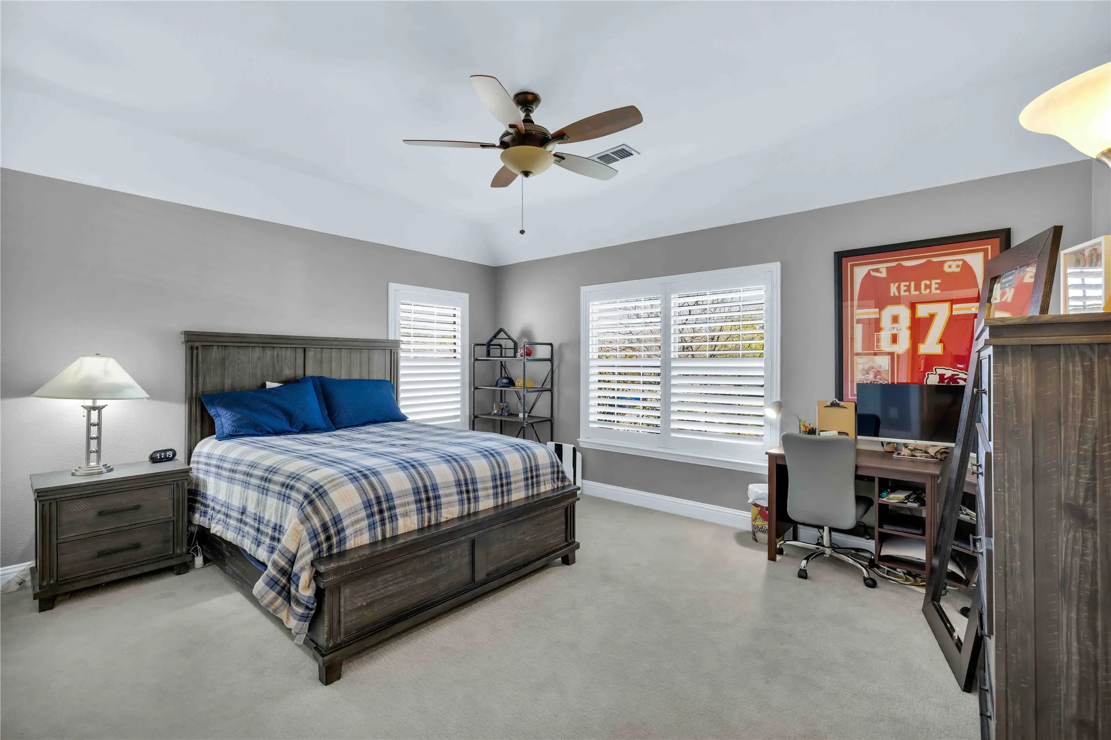 Room featuring a vaulted ceiling with a ceiling fan, two windows with plantation shutters, and light-toned carpet flooring