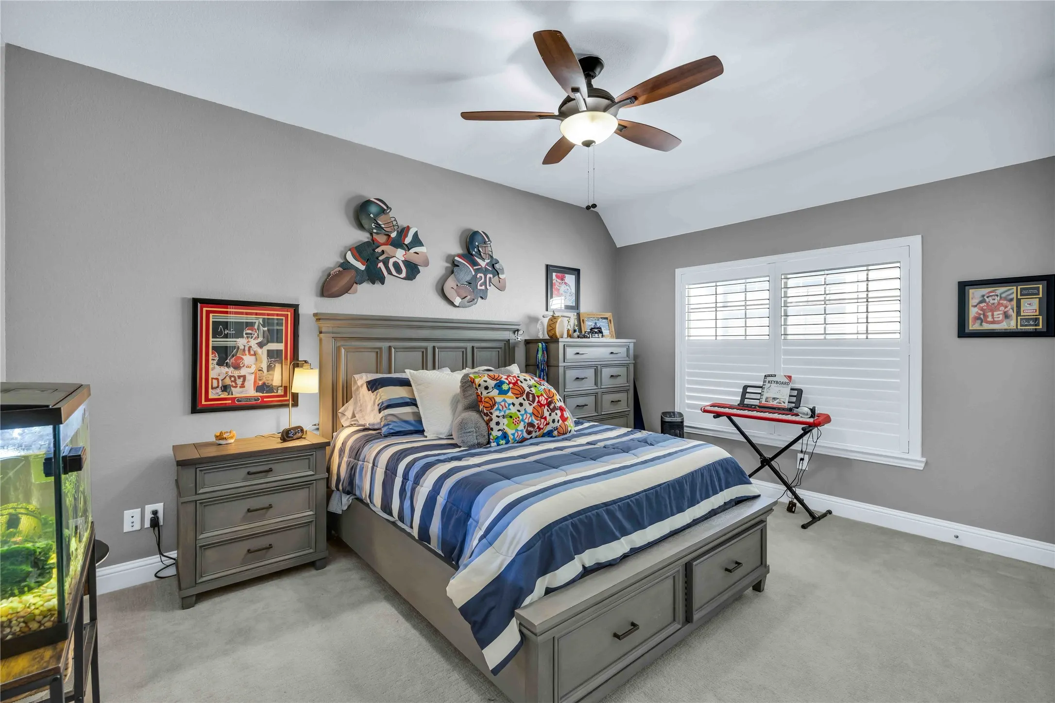 Carpeted bedroom featuring a vaulted ceiling with a ceiling fan, a window with plantation shutters, and a baseboard trim