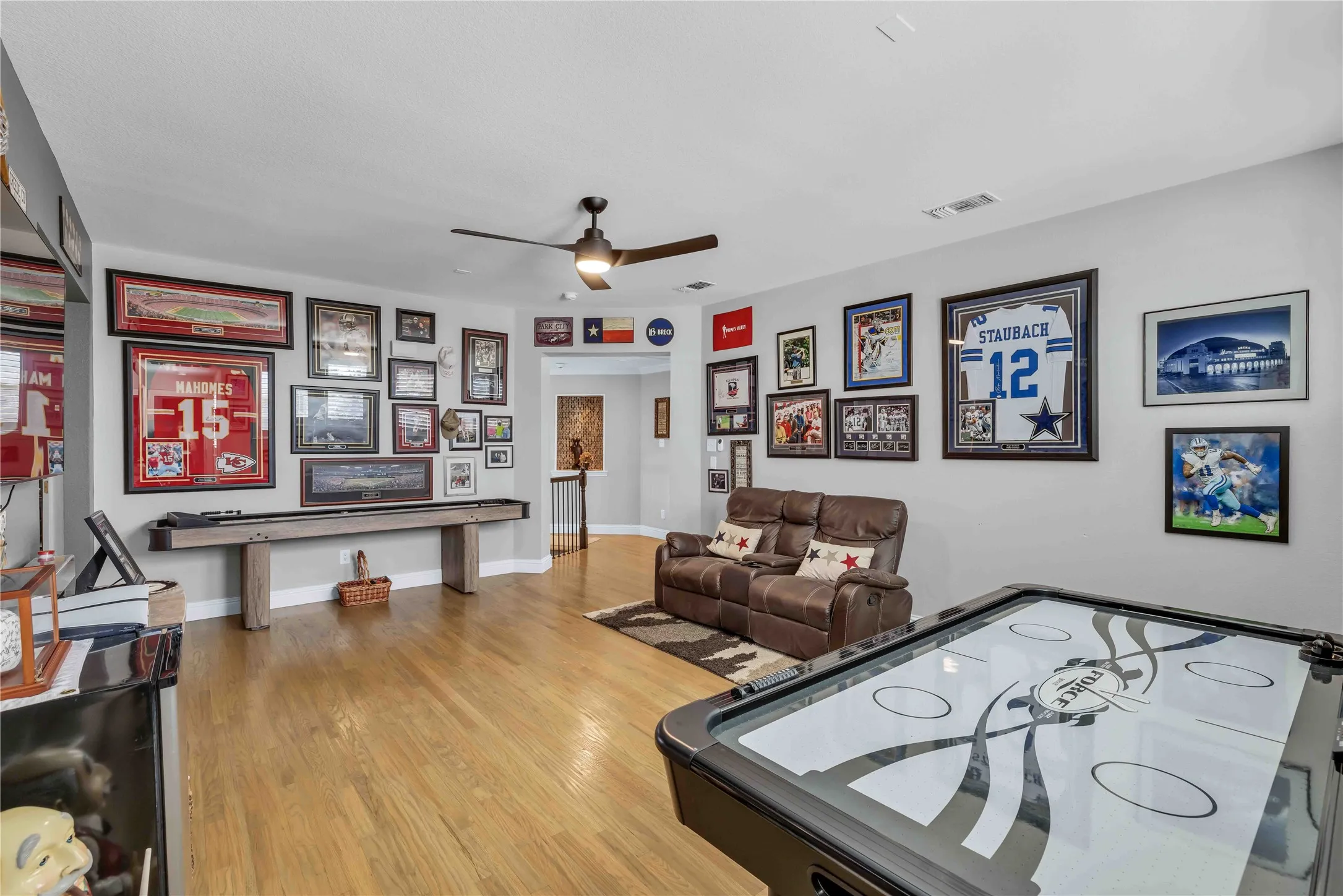 Spacious room featuring wood-finish flooring, light gray wall paint, and a ceiling fan