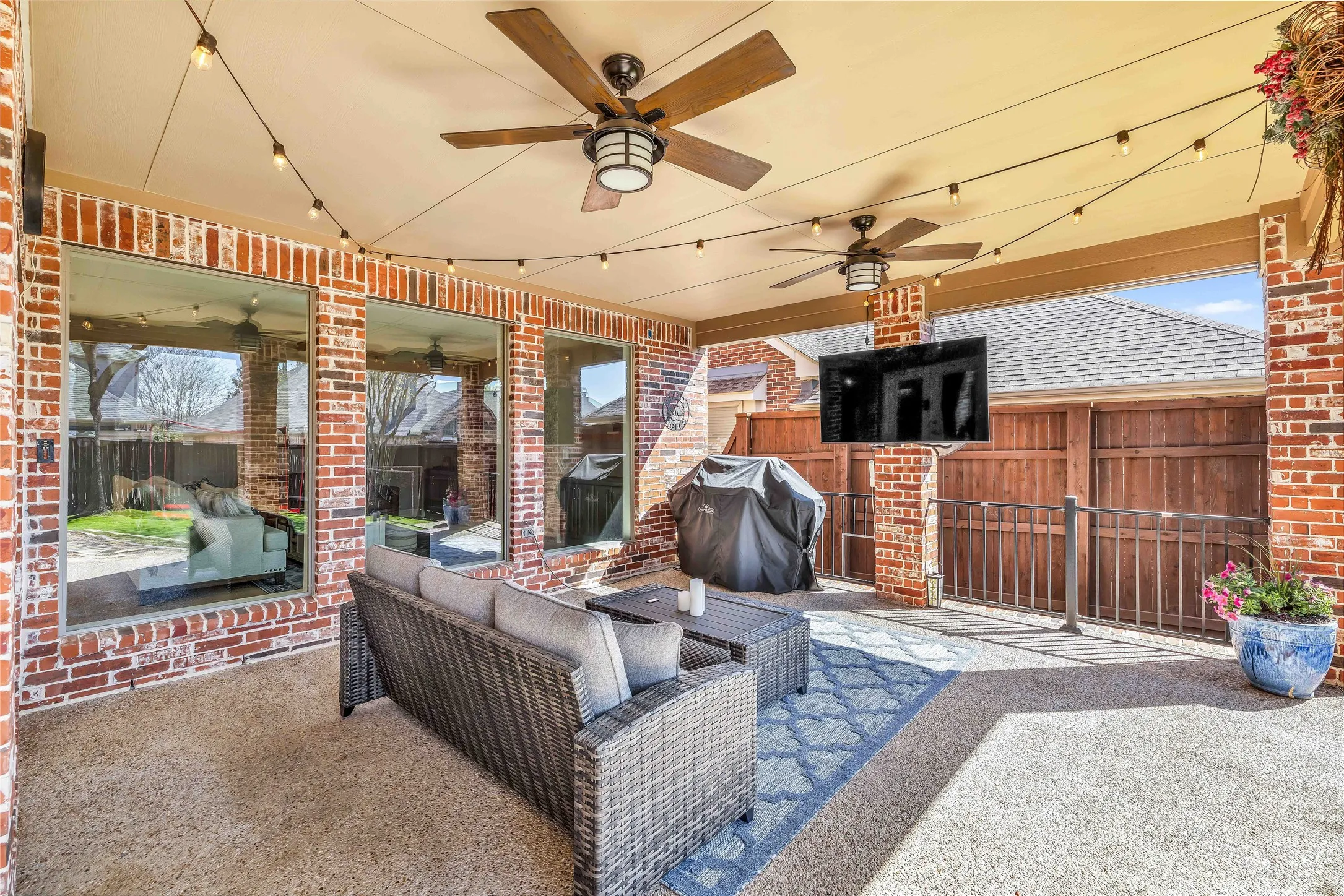 Covered patio featuring a textured concrete floor, brick columns, and a built-in television