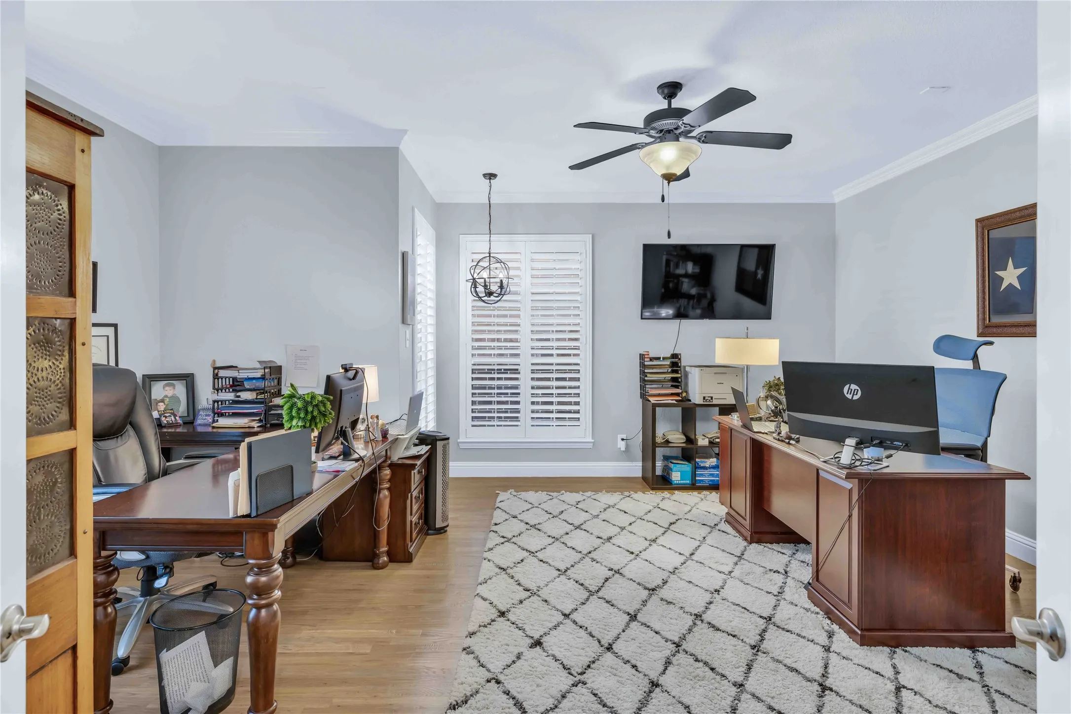 Kitchen island featuring a farmhouse sink, stainless steel appliances, pendant lighting, and light wood-finish flooring