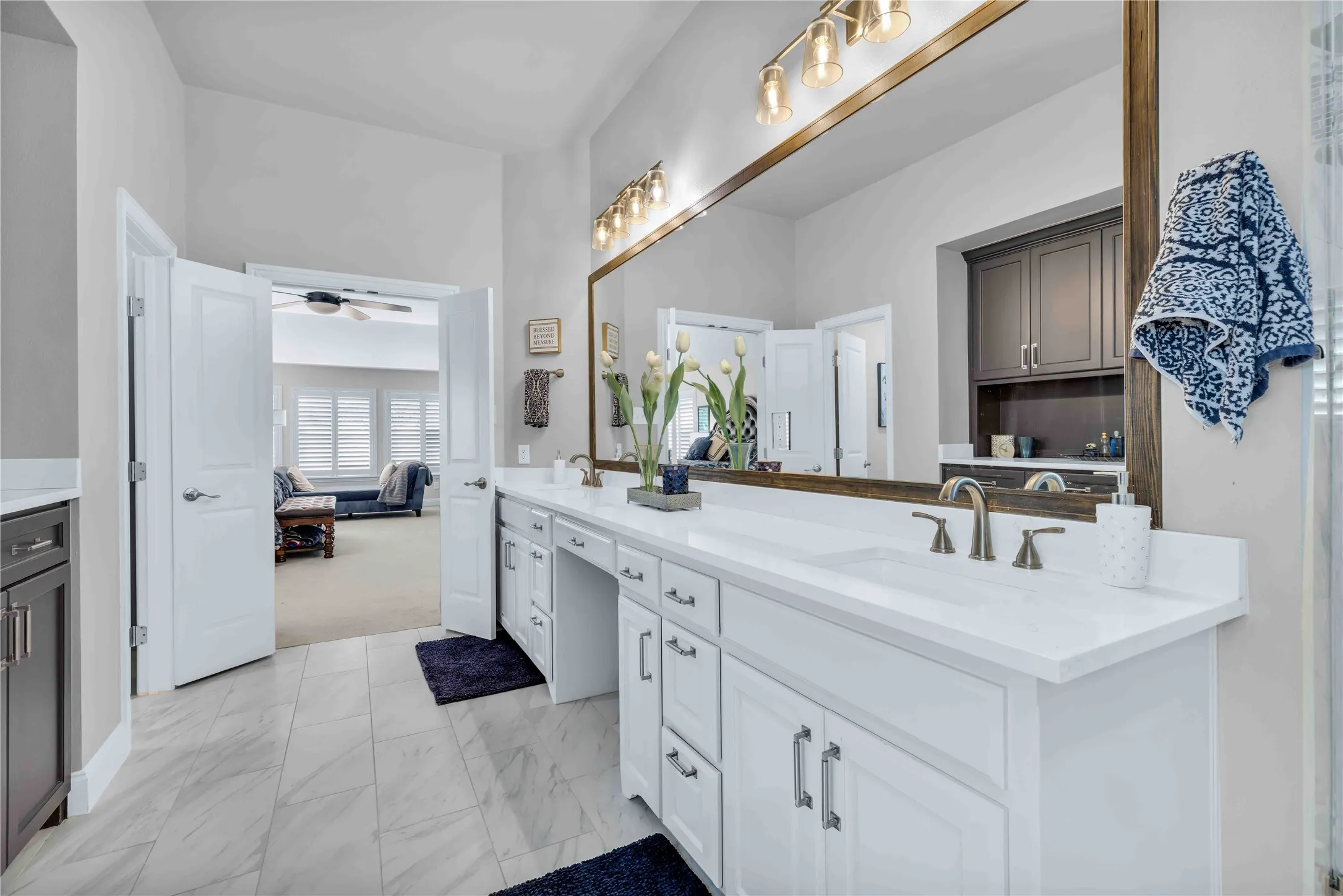 Dual vanity with white cabinetry, integrated sinks, brushed nickel fixtures, and a large framed mirror with overhead lighting