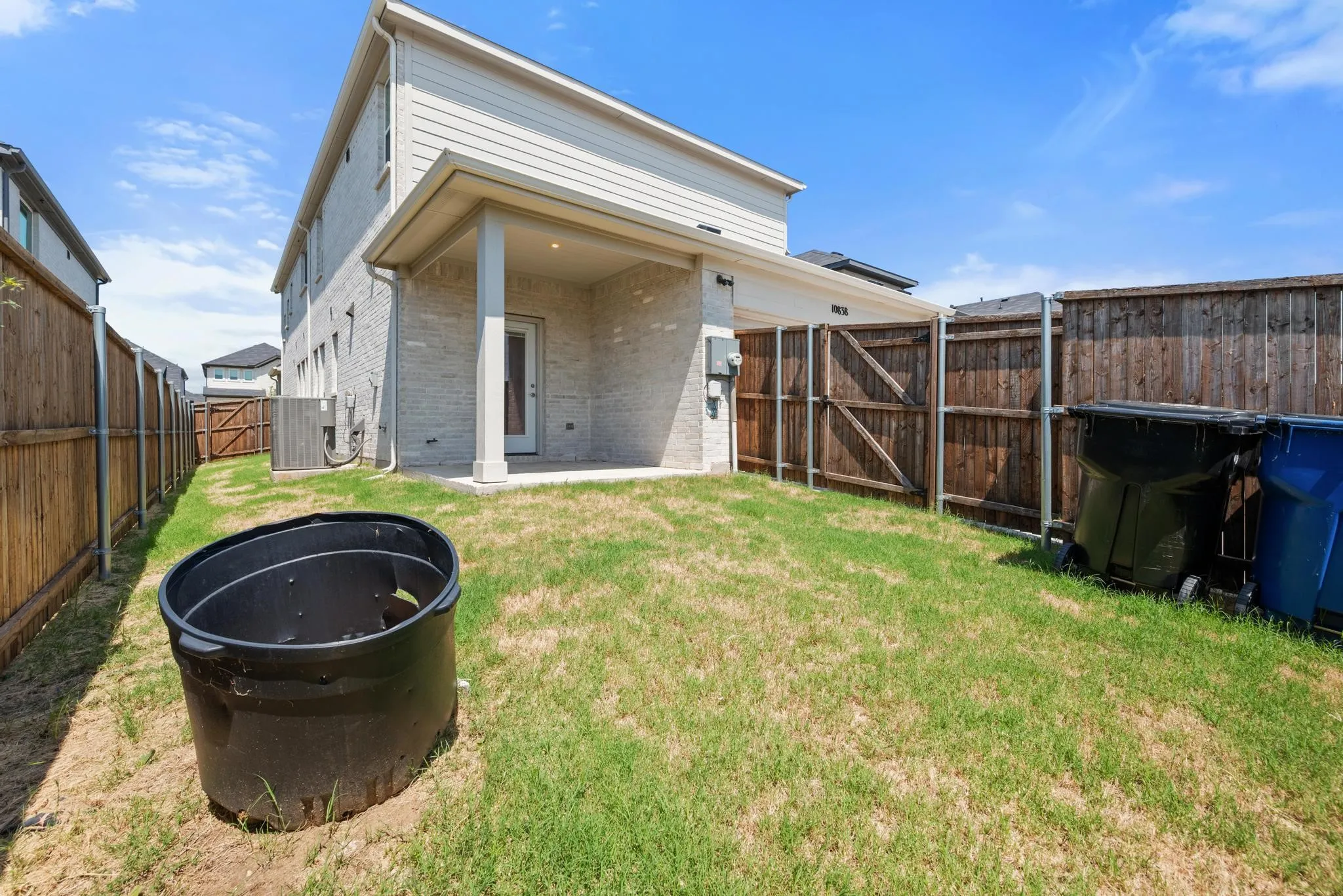 Expansive backyard featuring a covered patio, a manicured lawn, and natural wood fencing