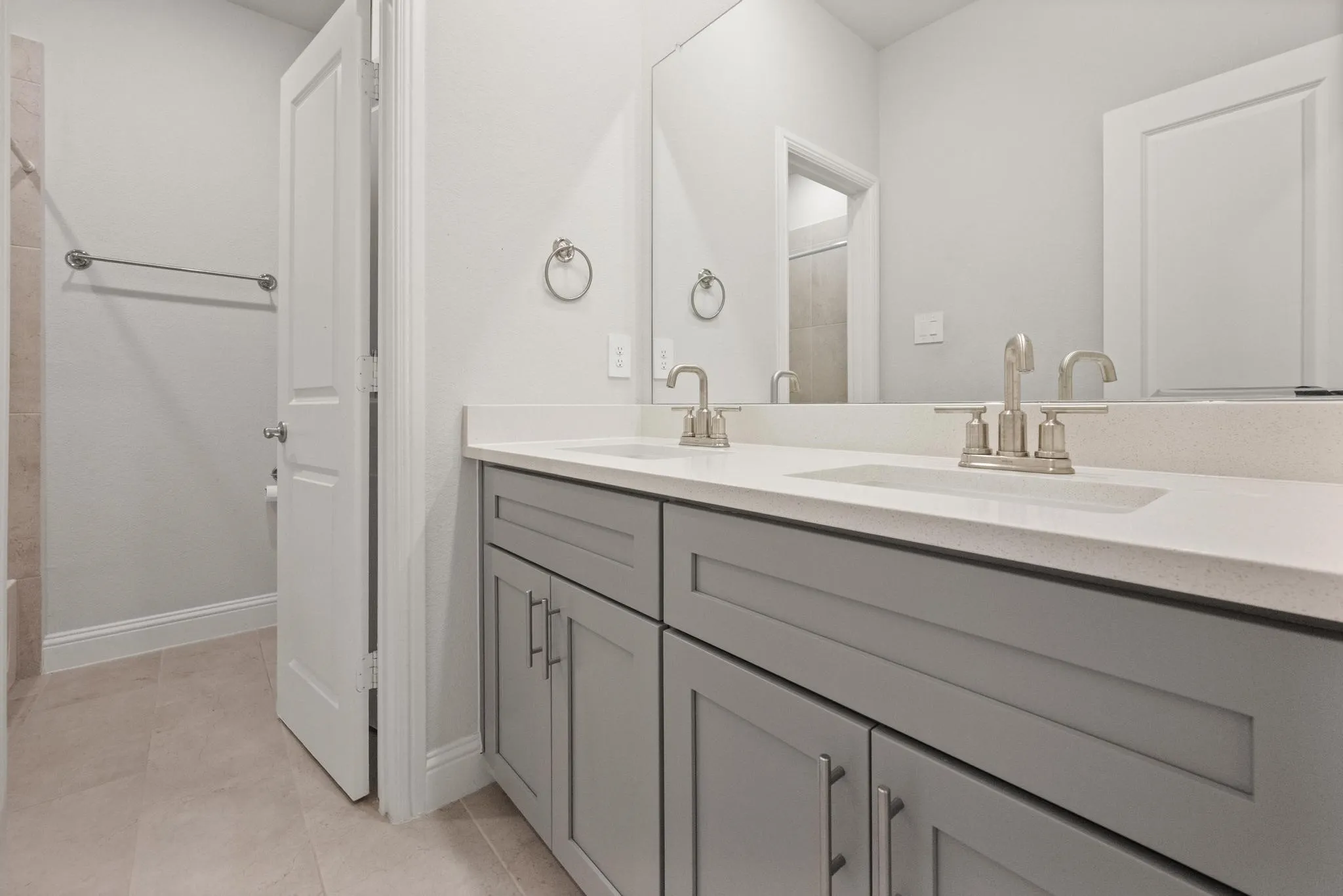 Double vanity with gray shaker cabinetry, brushed nickel hardware, light-toned countertop, and dual undermount sinks