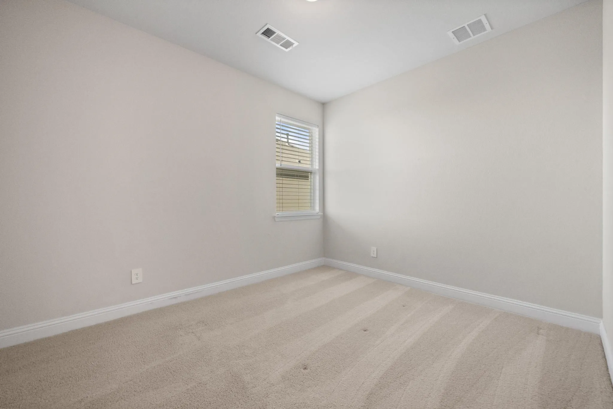 Neutral-toned carpet flooring with white baseboards and light-colored walls