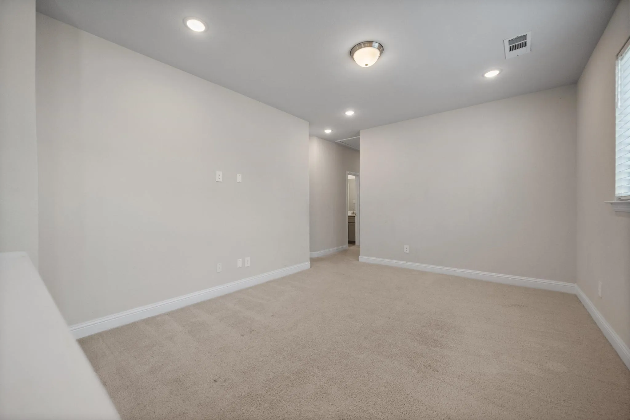 Carpeted interior space featuring recessed lighting, a ceiling-mounted light fixture, white baseboards, and a window with blinds