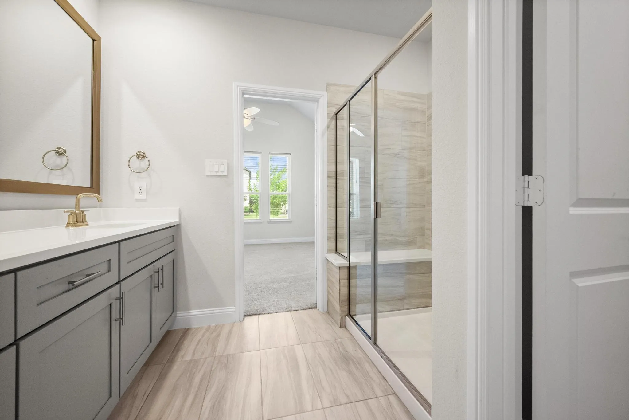 Bathroom featuring wood-finish flooring, a glass-enclosed shower with a built-in bench, a single vanity with a quartz countertop, and gray cabinetry