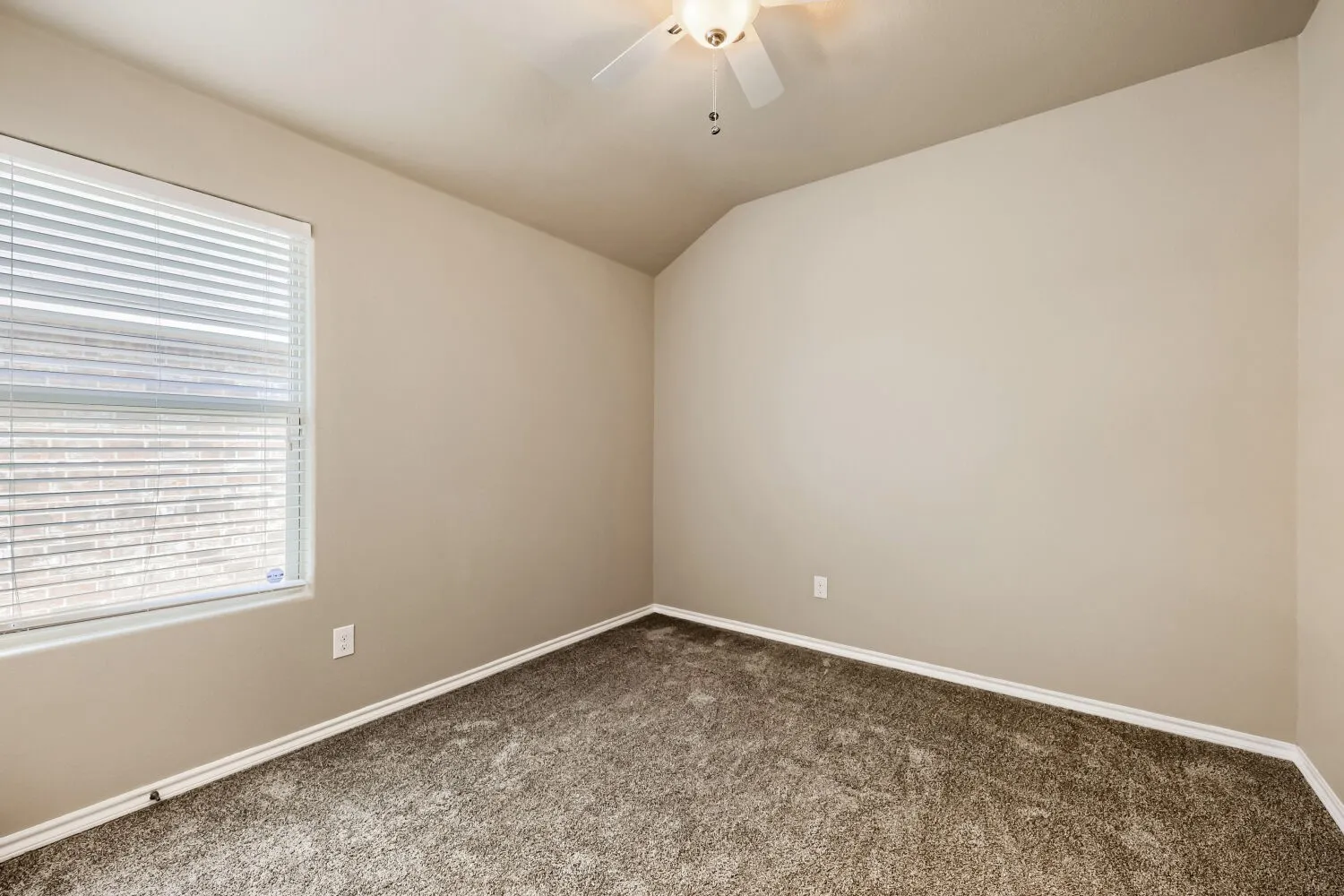 Room featuring textured carpet flooring, neutral painted walls, and a vaulted ceiling