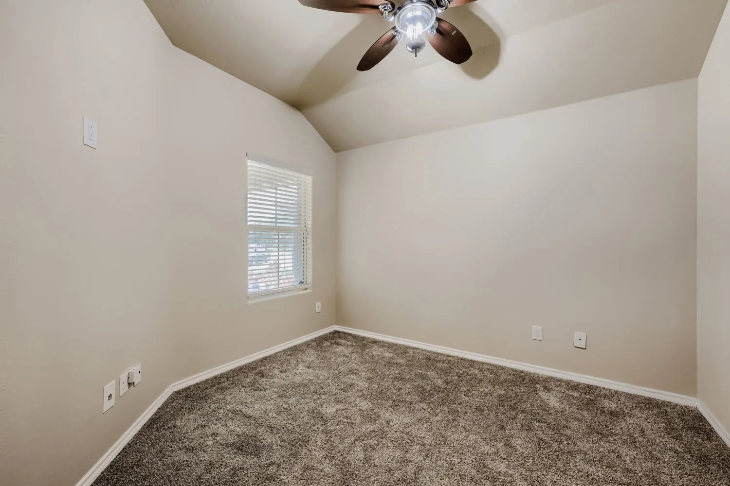 Carpeted room featuring a vaulted ceiling and ceiling fan with integrated lighting