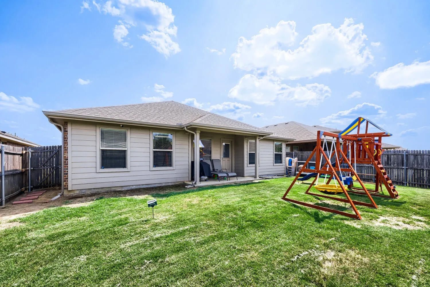 Fenced backyard featuring a manicured lawn, concrete patio, and a covered patio area