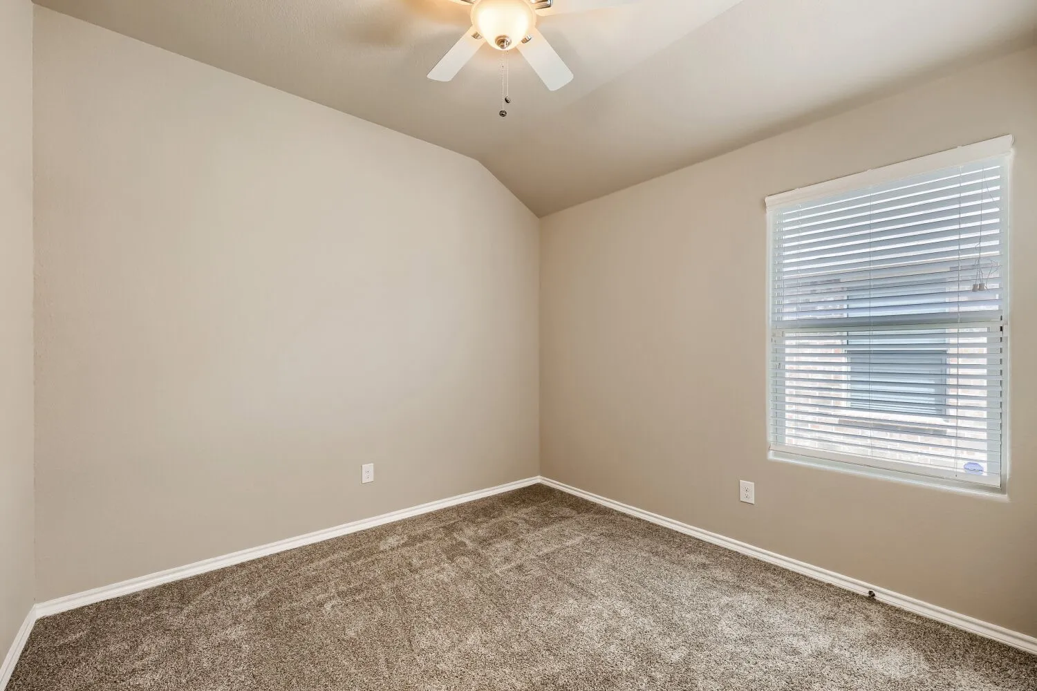 Carpeted room featuring a single window with horizontal blinds, light-toned walls, a white ceiling fan with integrated lighting, and white baseboards