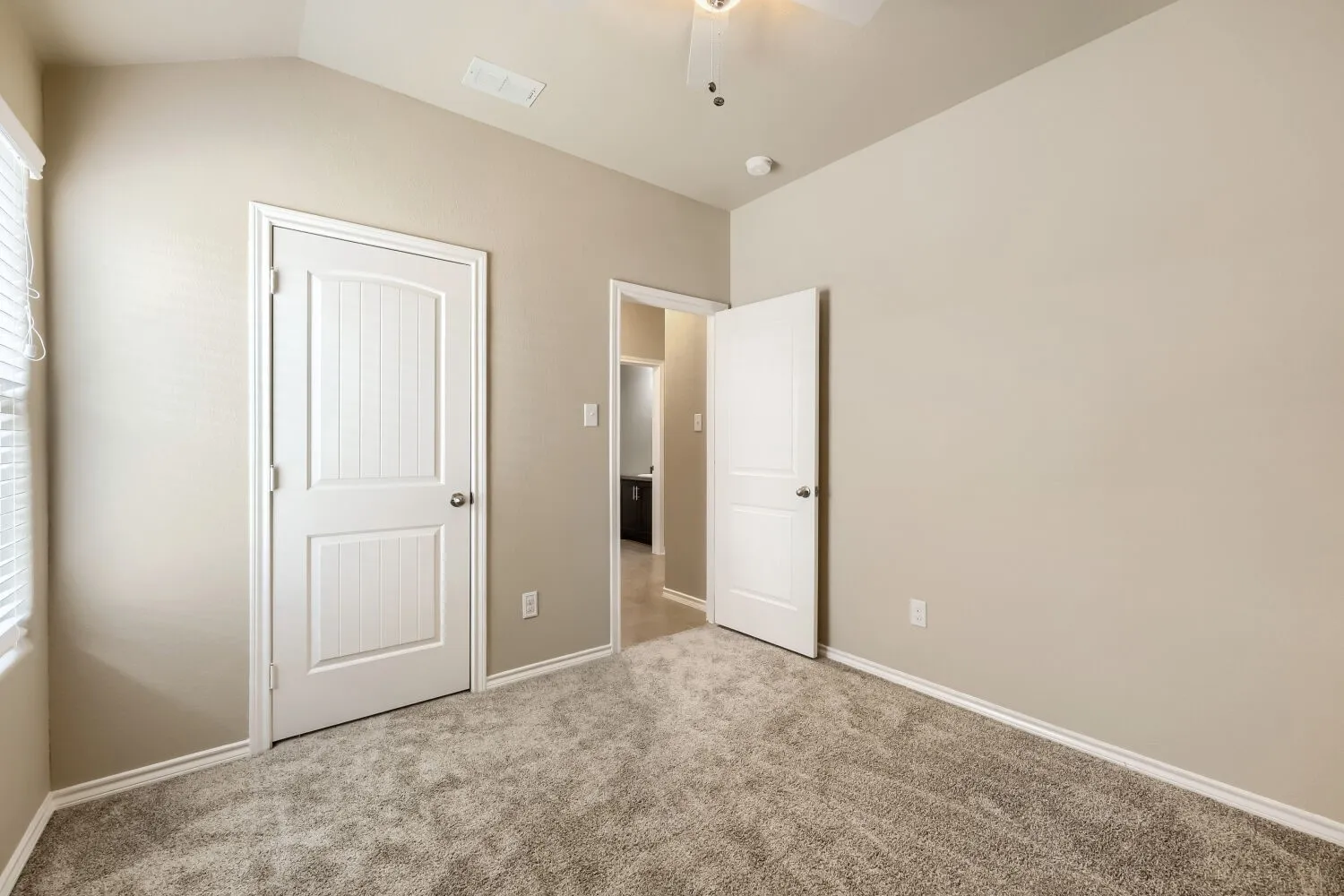 Carpeted room featuring a vaulted ceiling, white trim, and a ceiling fan
