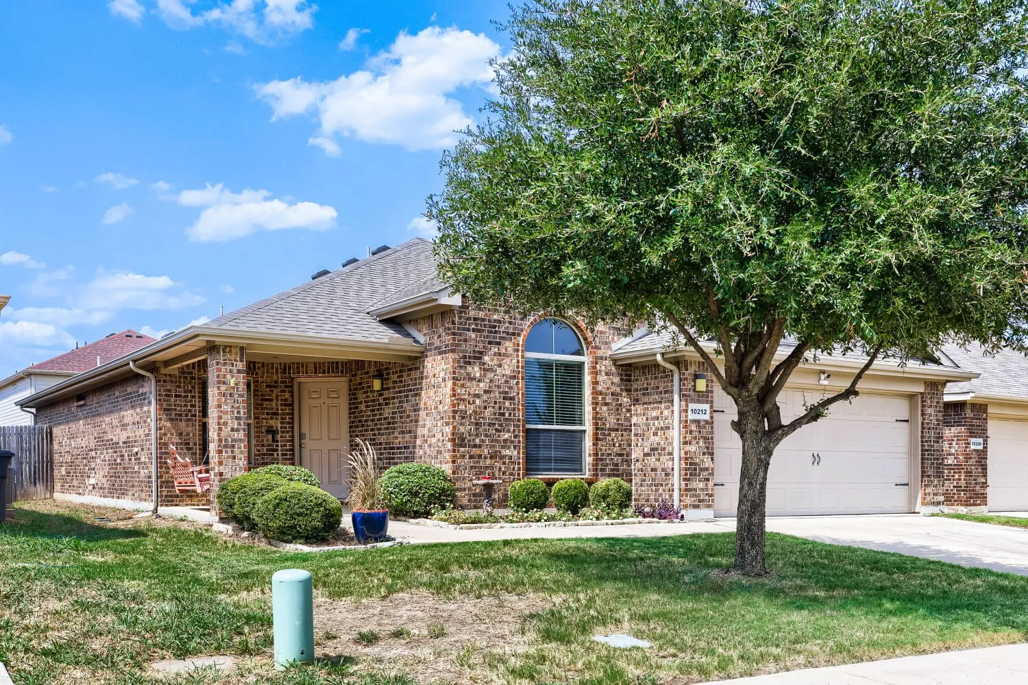 Brick exterior with a covered porch, arched window, and attached garage