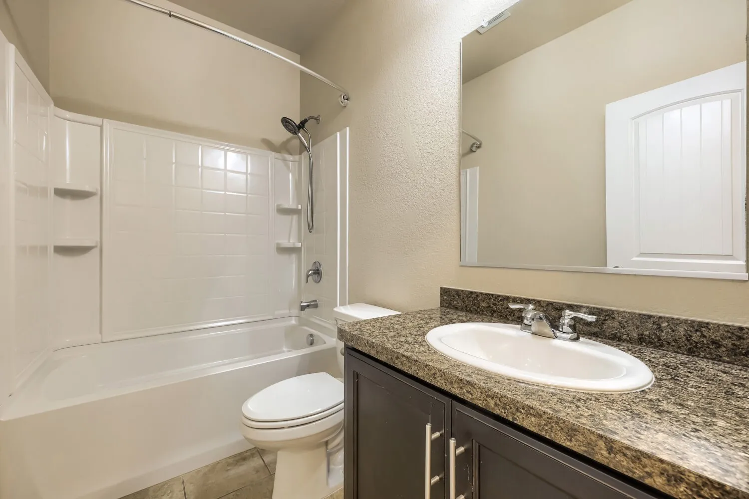Modern bathroom featuring a dark-finish vanity with granite-style countertop, oval undermount sink, and polished chrome fixtures