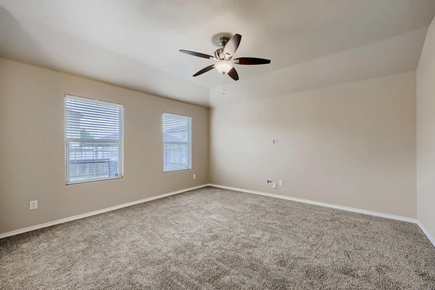 Spacious room featuring vaulted ceilings, neutral-toned walls, and plush carpet flooring