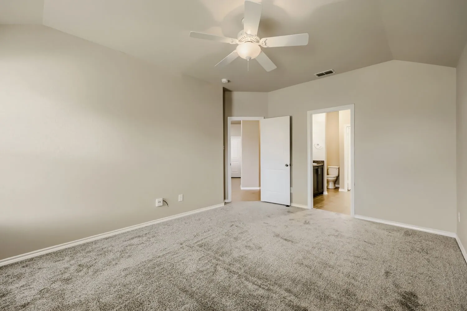 Spacious room featuring vaulted ceilings, light gray wall paint, and gray carpet flooring