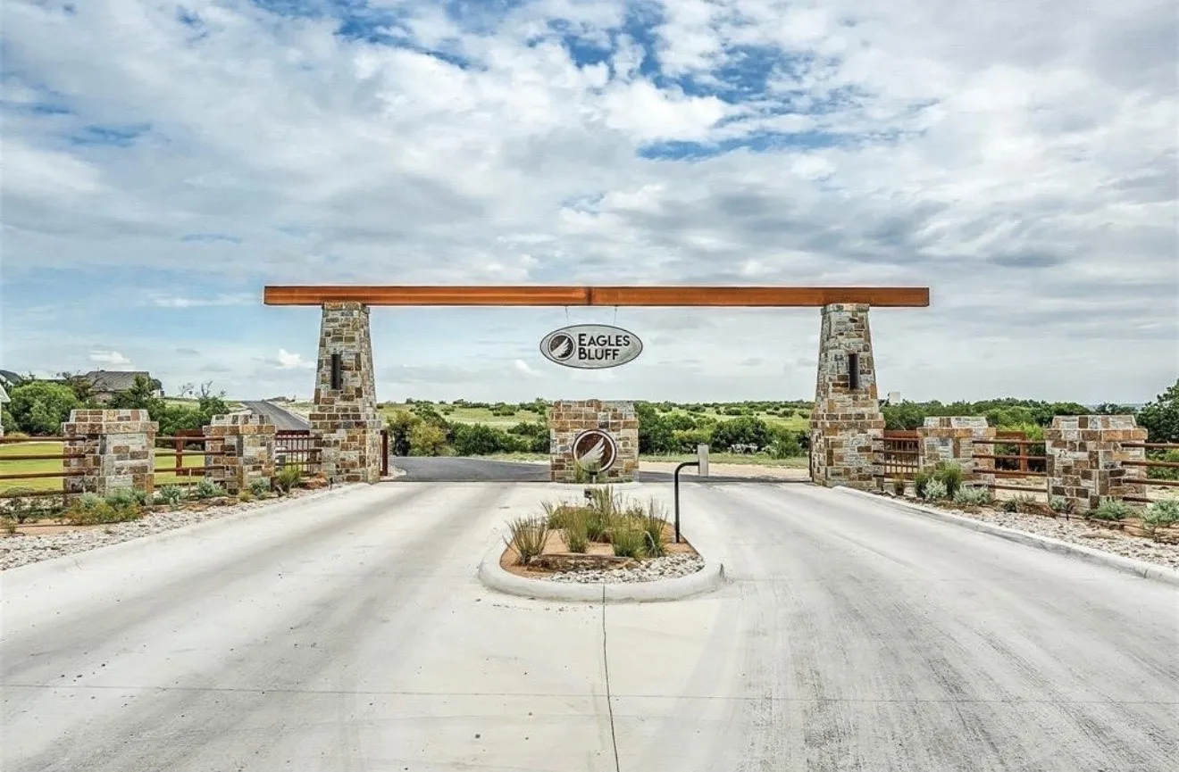 Impressive stone and timber entry gate featuring substantial stone pillars and a wood-beam overhead structure, anchoring the property's grand entrance