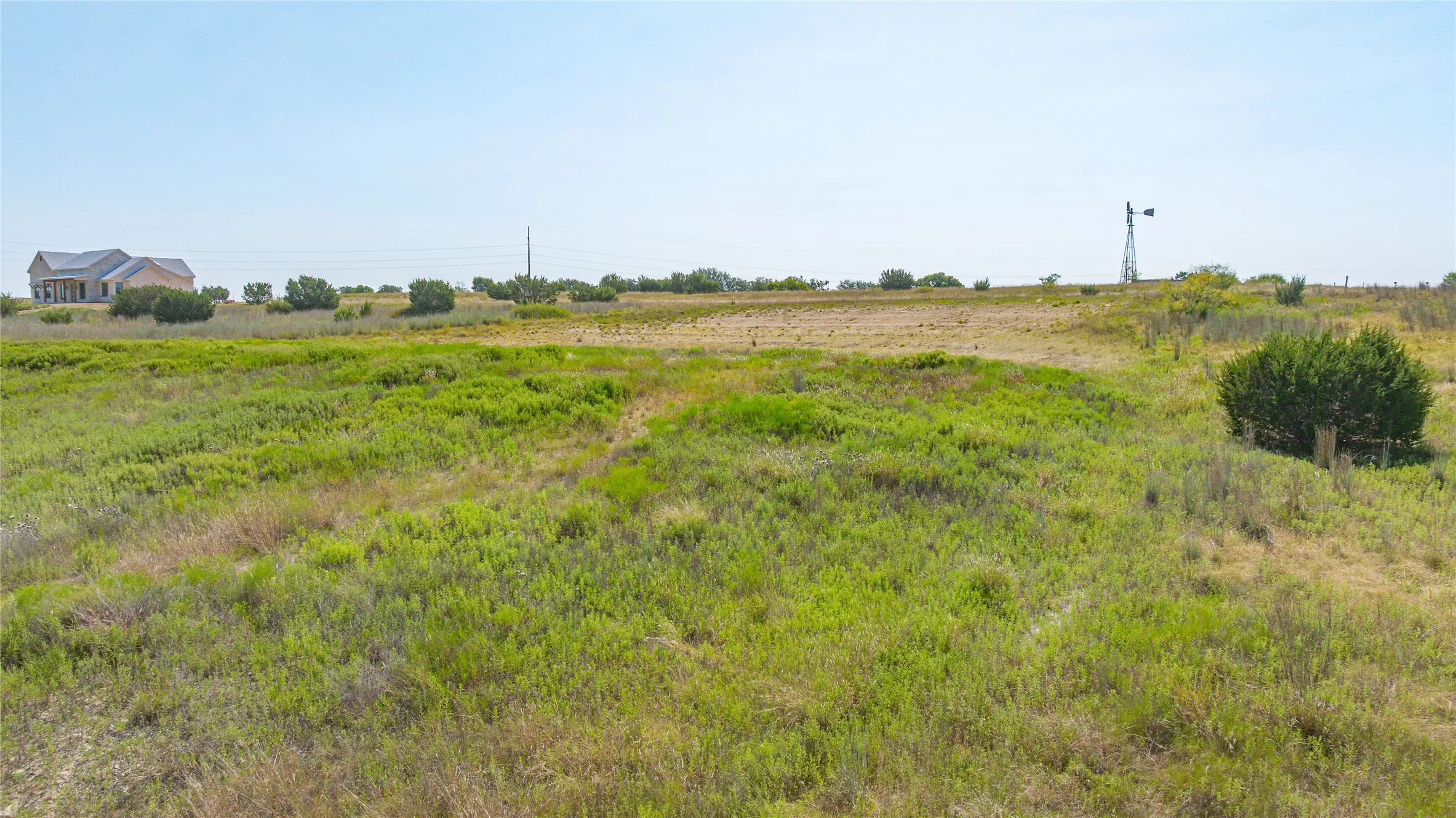 Expansive undeveloped land featuring natural vegetation and distant structures