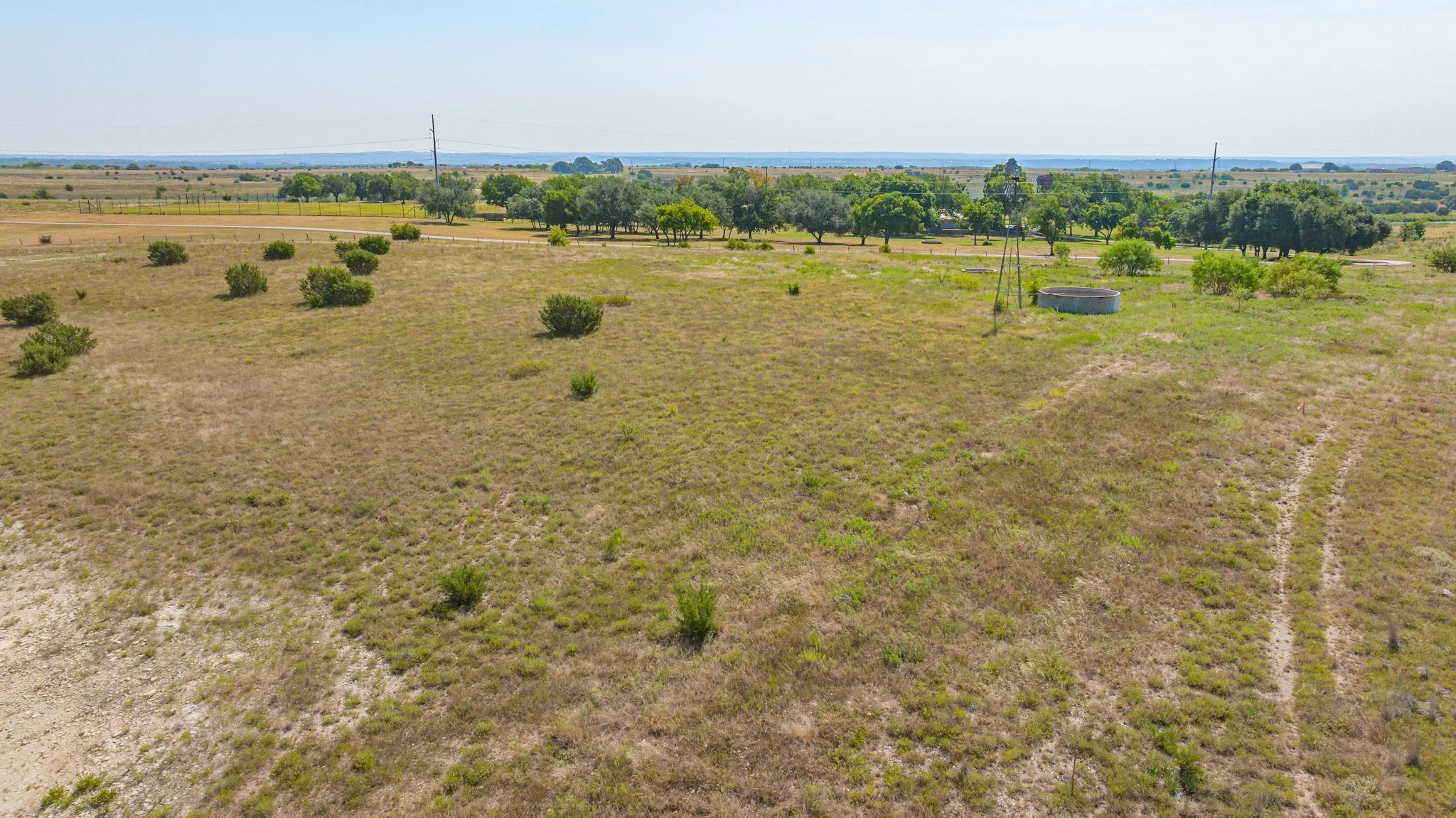 Expansive acreage featuring natural vegetation, mature tree lines, and a water tank structure