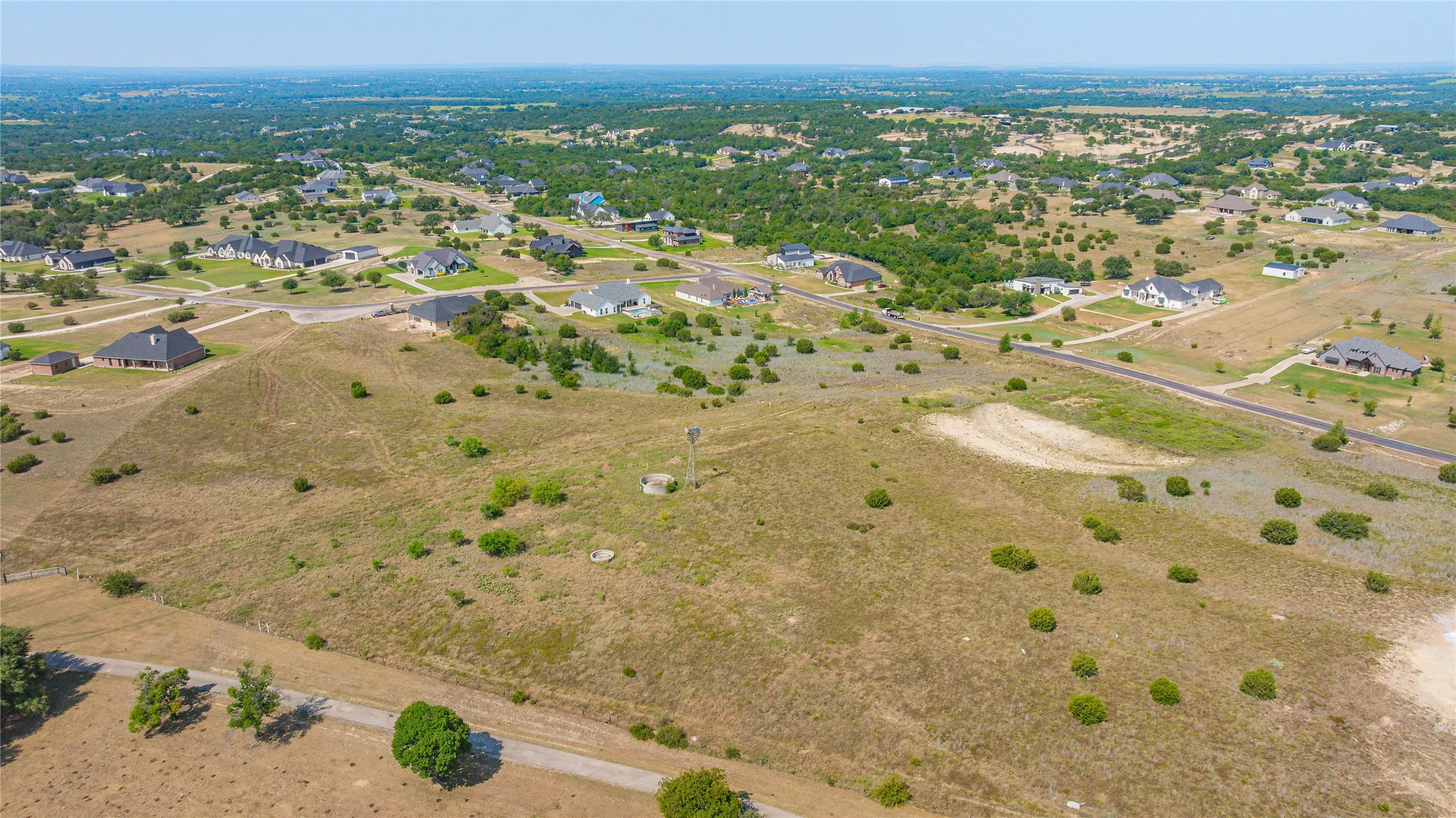 Expansive undeveloped land featuring a windmill structure and varied terrain with sparse vegetation