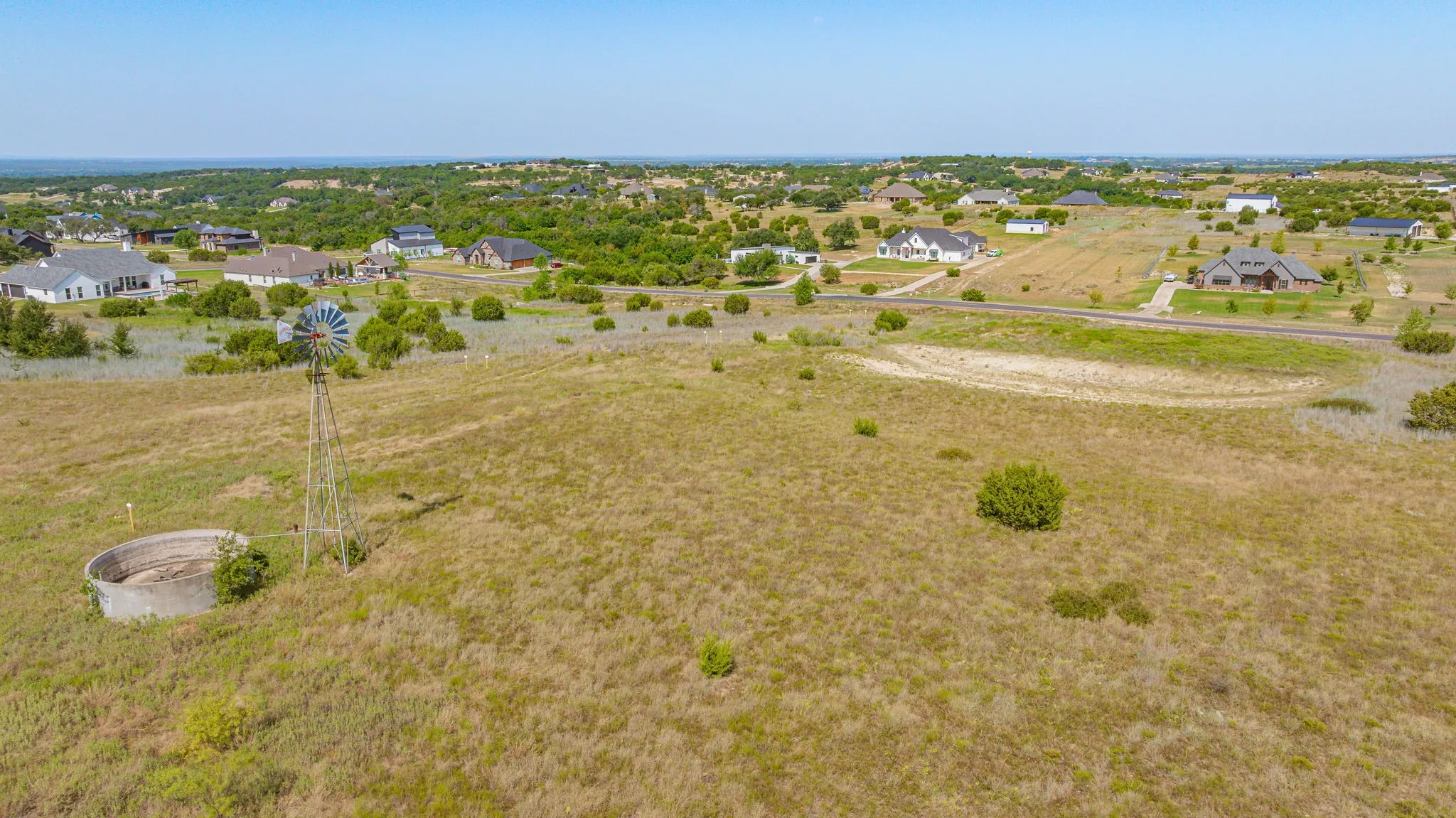 Expansive acreage featuring mature oak trees, open pastureland, and a working windmill