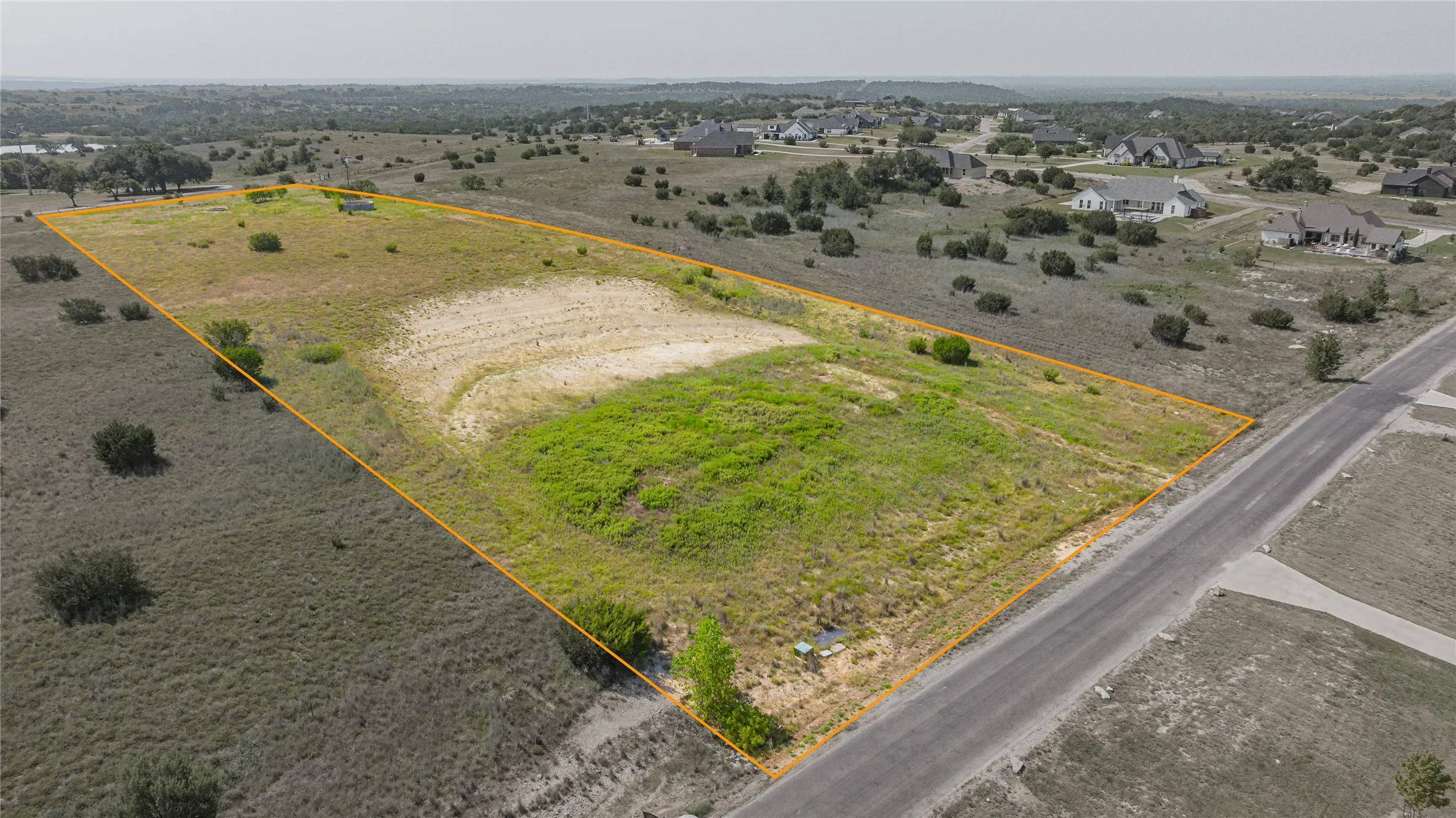 Expansive vacant land parcel featuring approximately 40+ acres of cleared and grassed acreage with scattered mature trees throughout