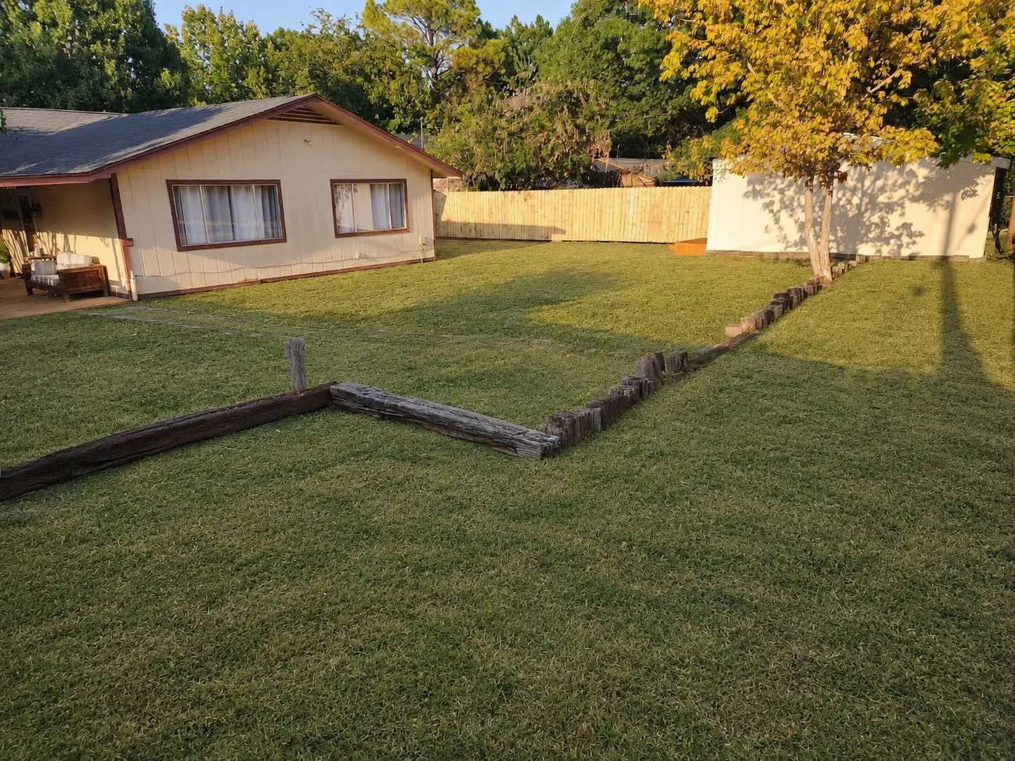 Expansive lawn with mature trees and a wood privacy fence