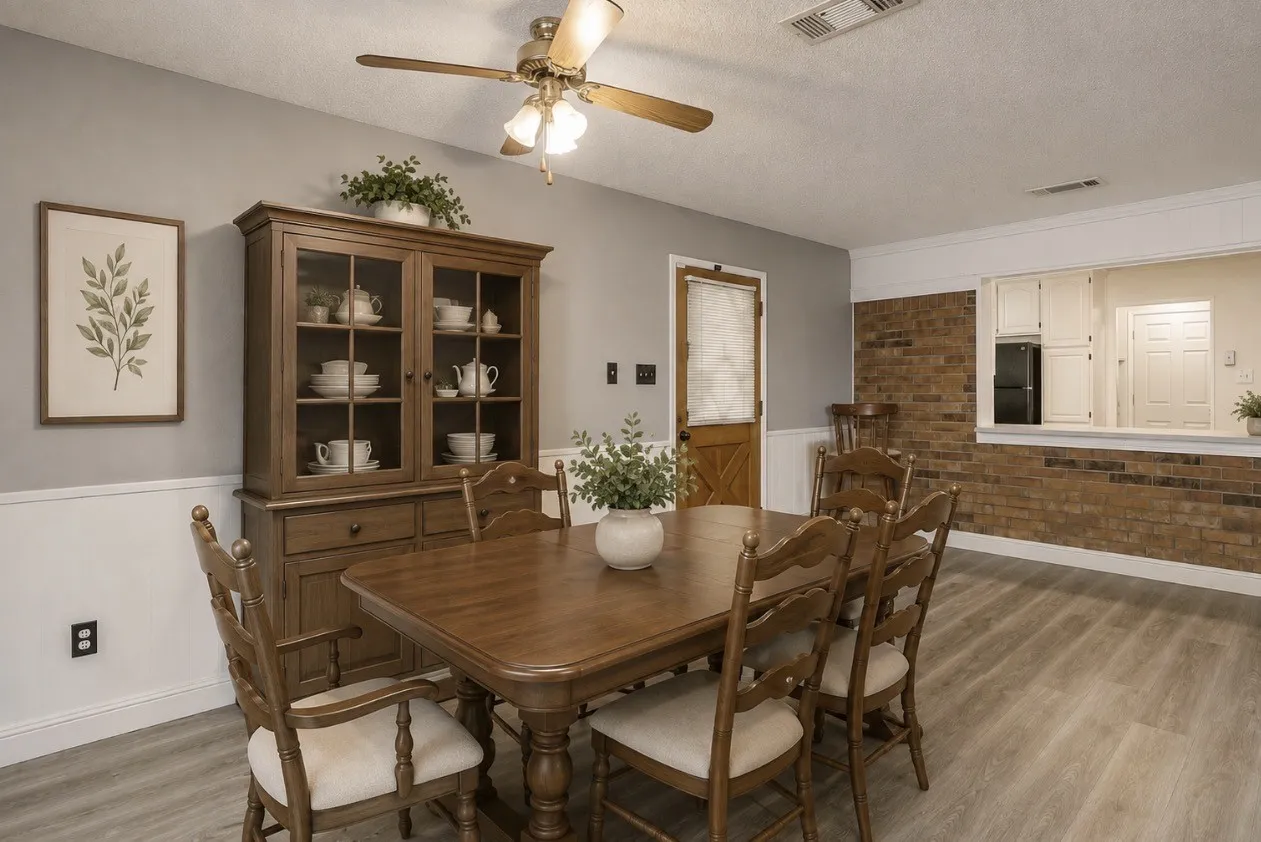 Virtually staged. Wood-finish flooring, half-wall brick accent, white wainscoting, and a ceiling fan with integrated lighting