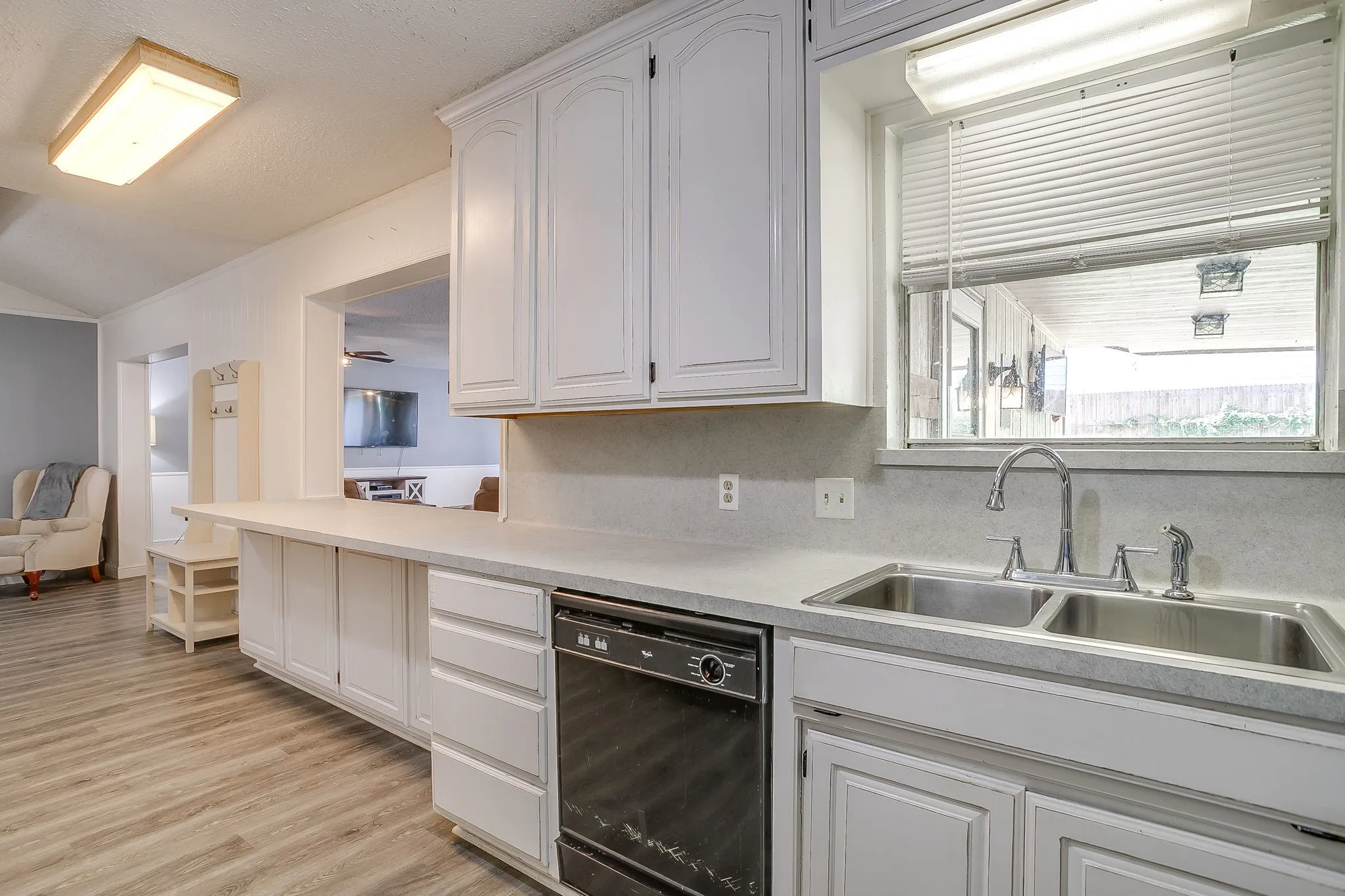 Kitchen featuring light-finish cabinetry, a dual basin stainless steel sink with gooseneck faucet, light-tone countertops, and a black dishwasher